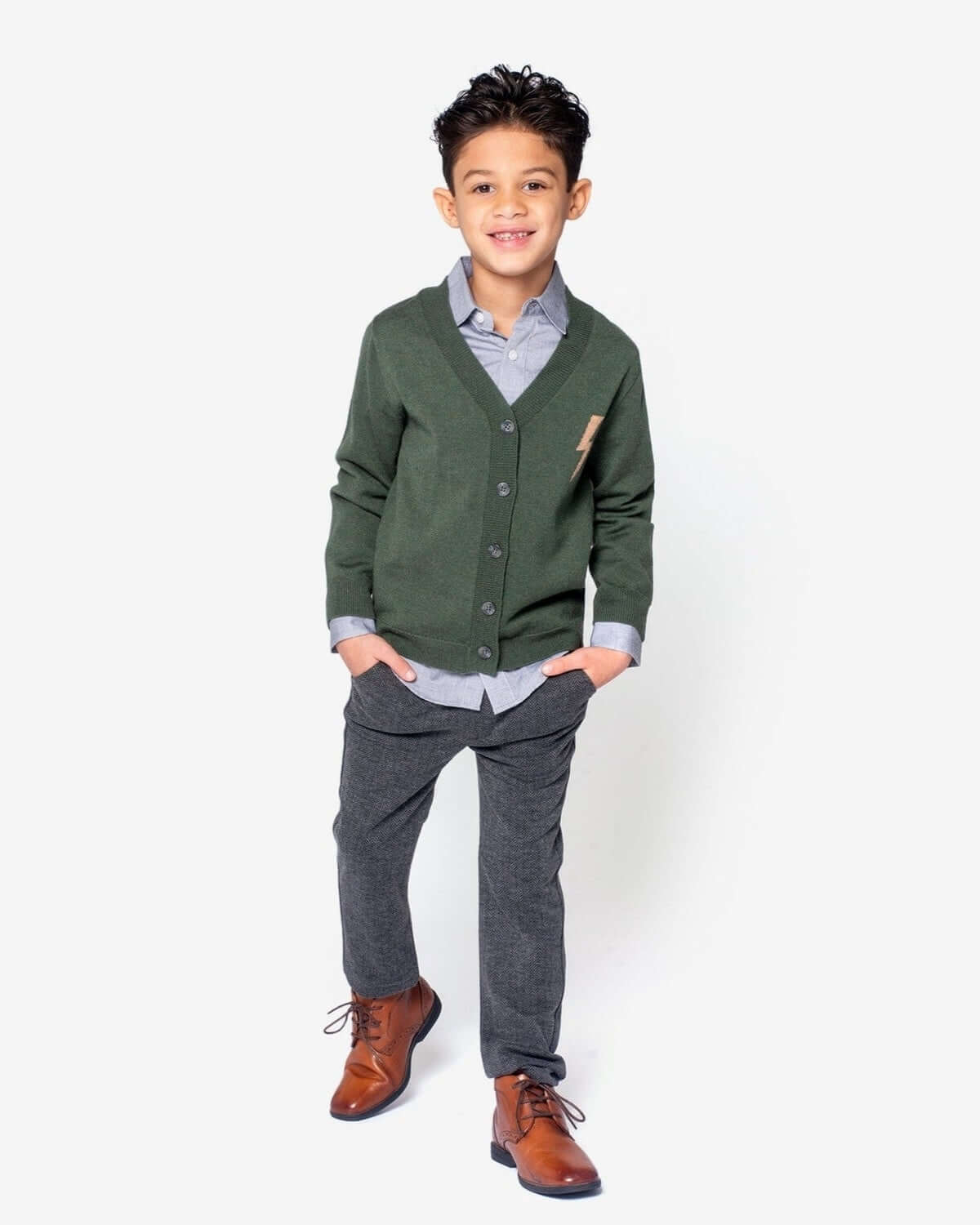 Boy wearing charcoal herringbone everyday stretch pants with a green cardigan and brown shoes.