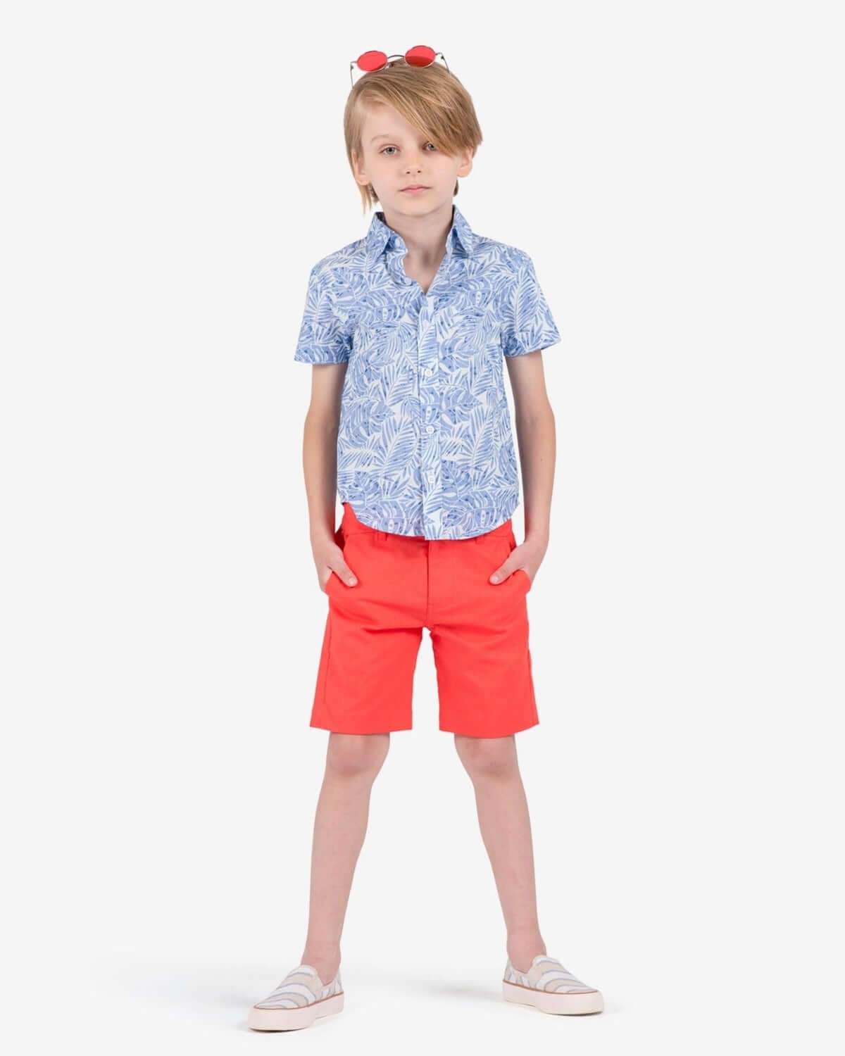 Stylish kid rocking bright coral trouser shorts with a fun blue patterned shirt—Summer vibes for back to school! Kids clothes at their best.
