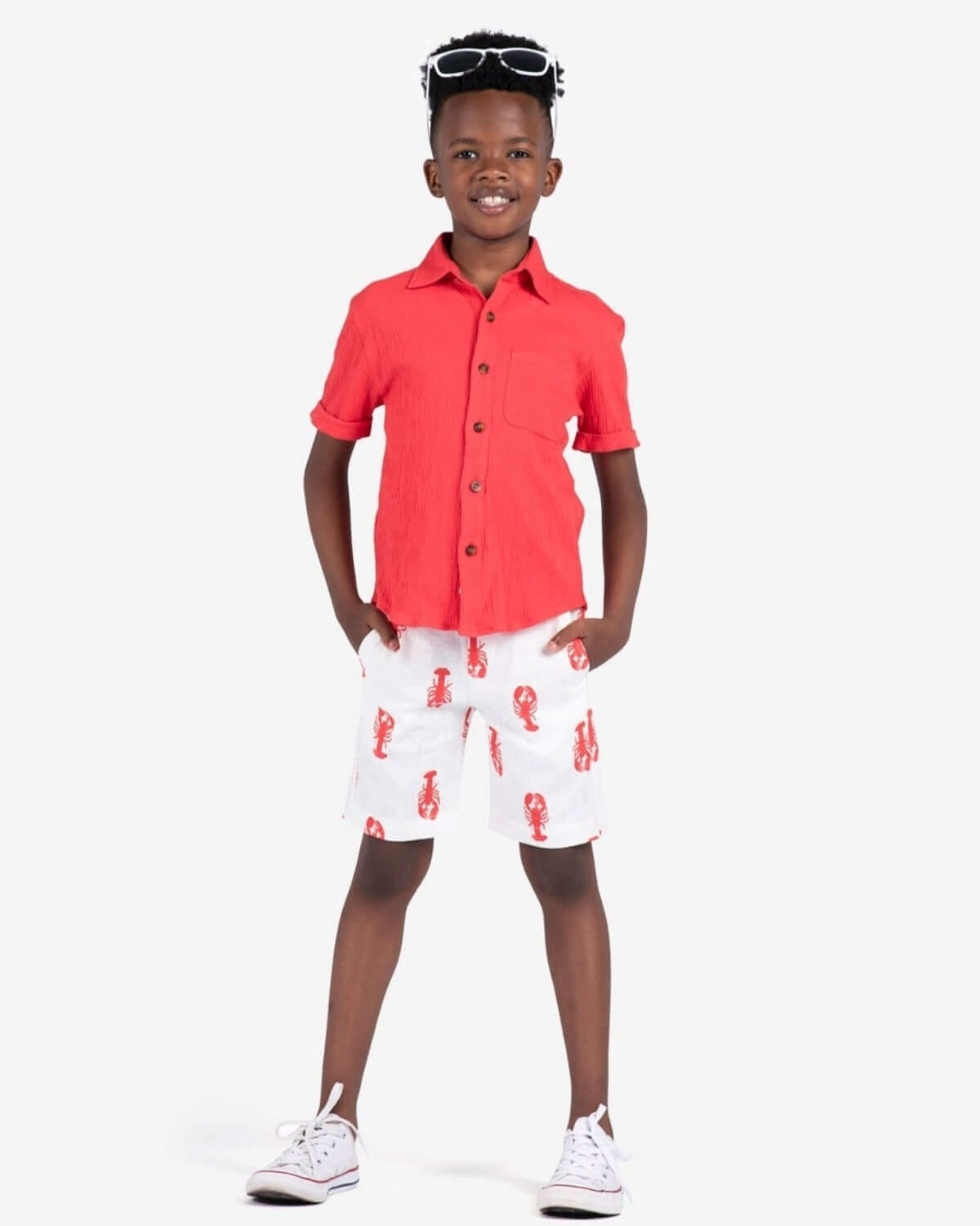 Stylish kid in a coral shirt and lobster pattern trouser shorts—fun, high-quality kids clothes for summer adventures!