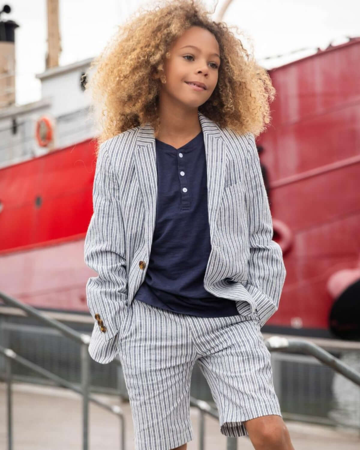 Confident kid in stylish navy striped suit set, ready for summer adventures and back to school fun in high-quality kids clothes.