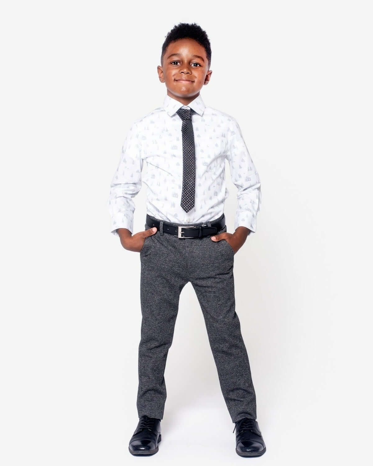 A boy wearing Noir Micro Plaid Stretchy Suit Pants, white shirt, and a tie, looking stylish and confident.