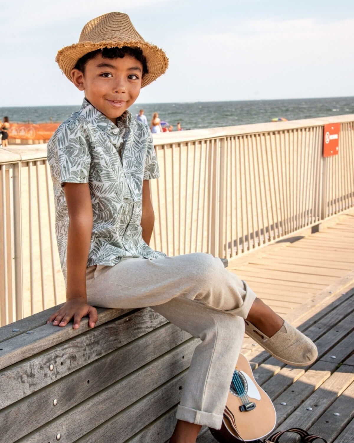 Stylish boy in a straw hat and beachy shirt, rocking linen beach pants—perfect for sun-filled adventures!