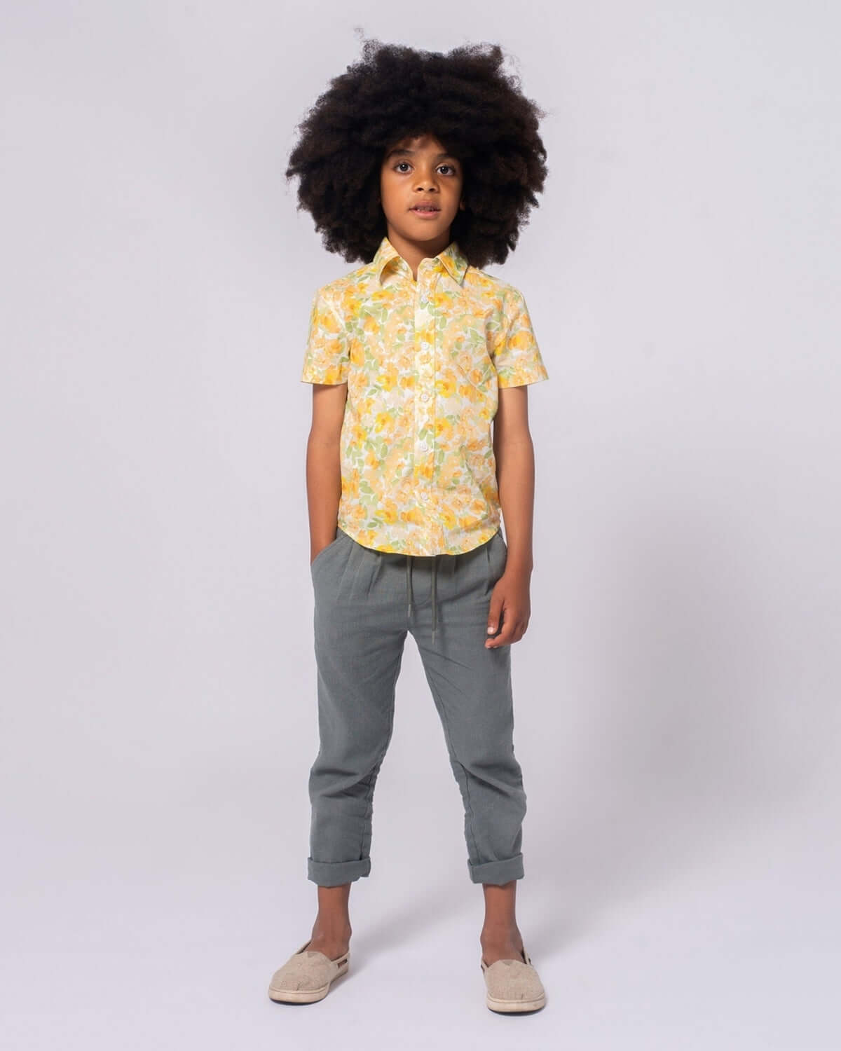 Stylish boy in vibrant yellow floral shirt and sage linen pants for playful back-to-school adventures.