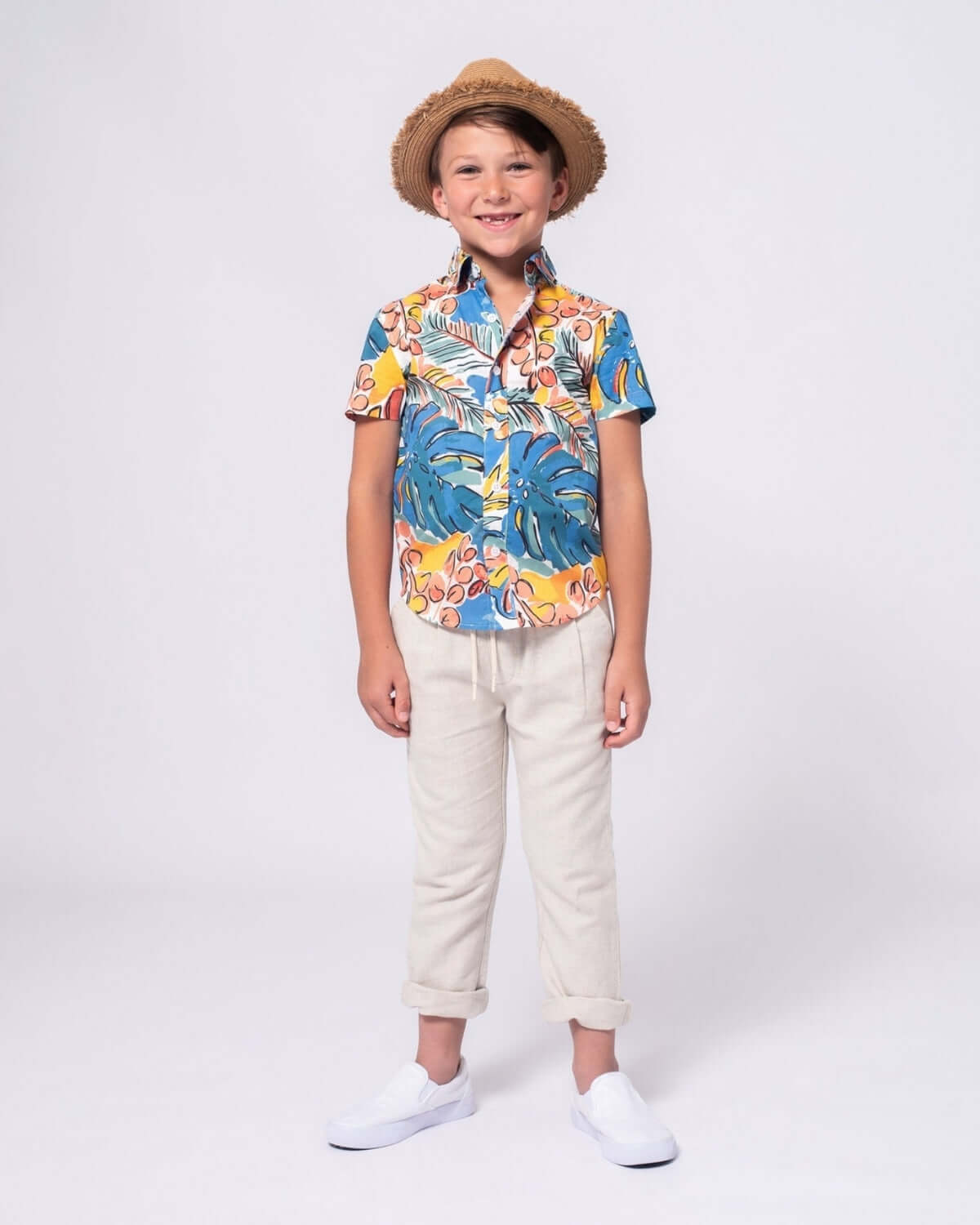 Stylish boy rocking a colorful tropical shirt with sand linen resort pants, ready for summer adventures!