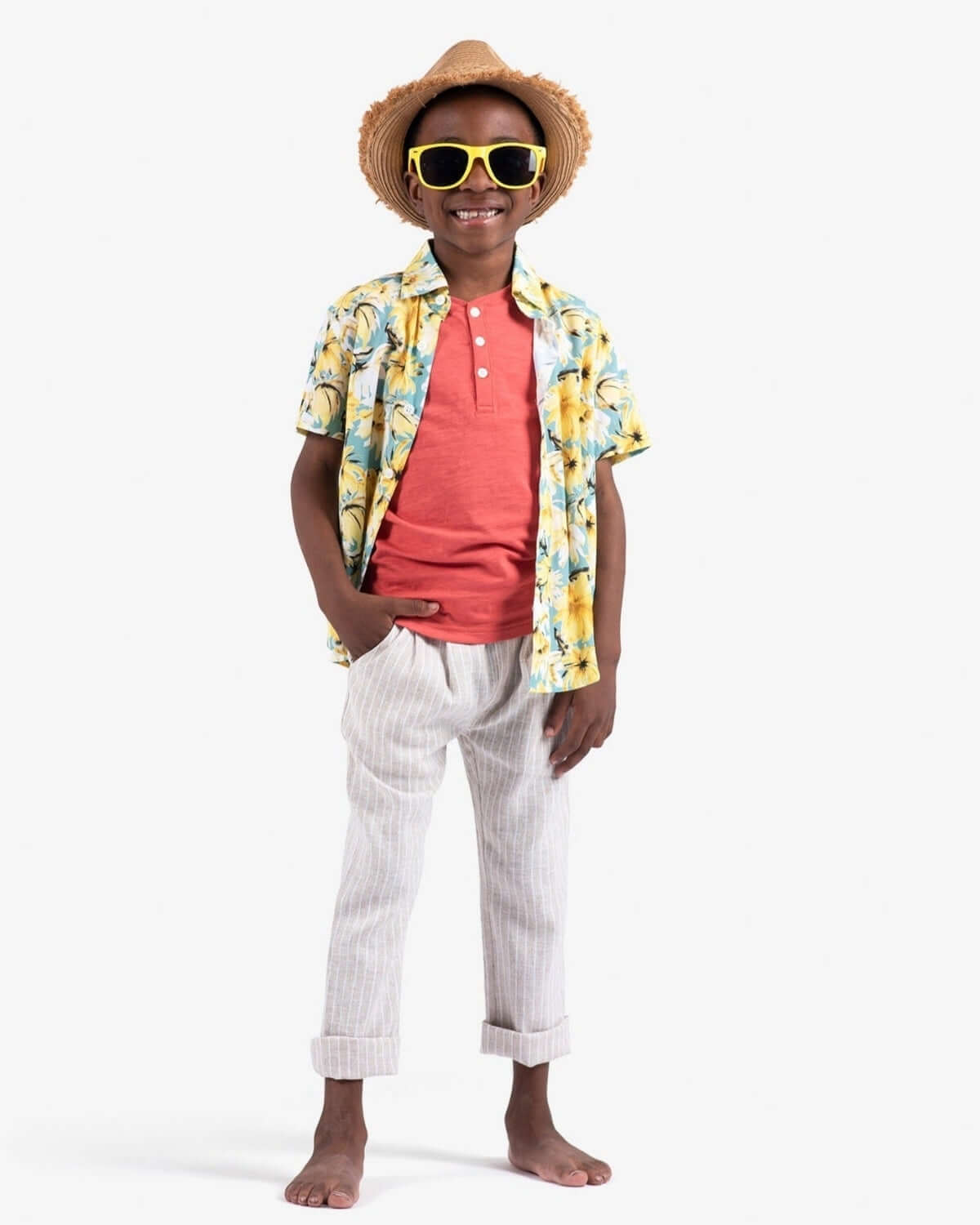 Stylish kid rocking bright resort wear with striped pants, tropical shirt, and oversized sunglasses—fun high-quality kids clothes!