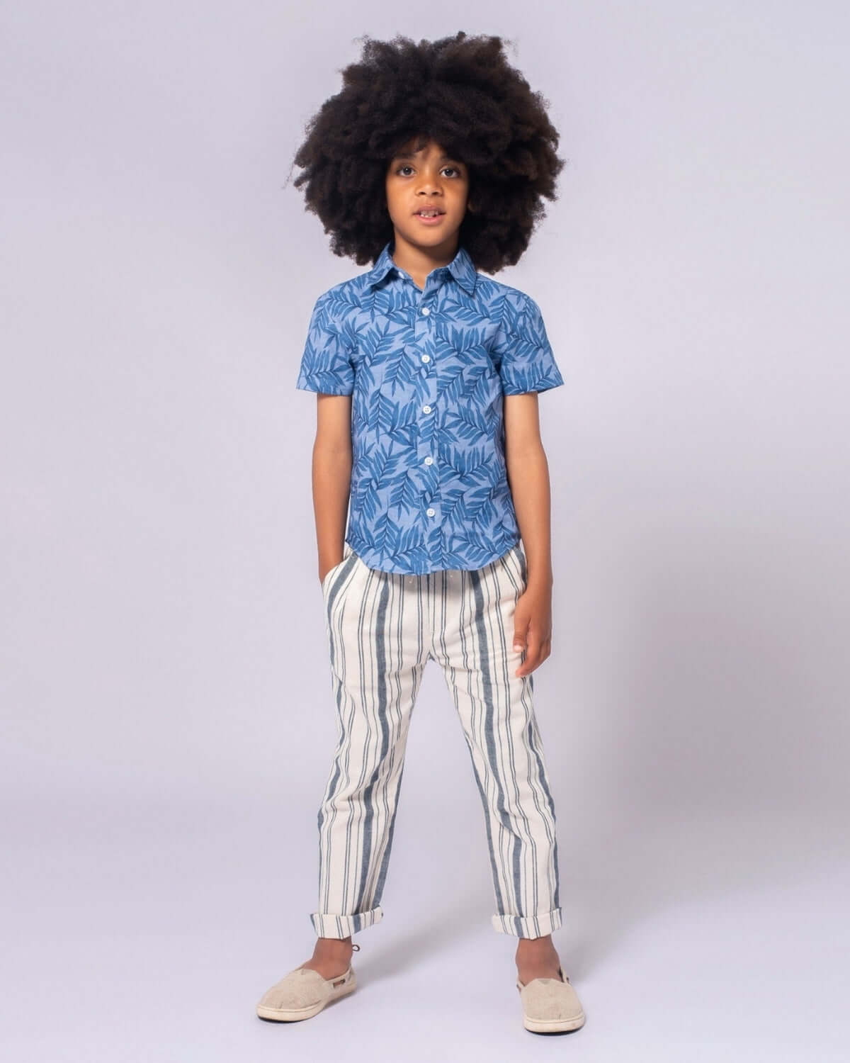 Stylish kid in blue tropical shirt and seaside stripe linen pants, perfect for trendy back-to-school adventures!