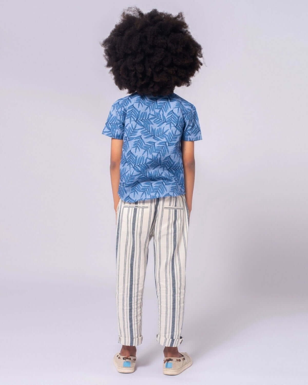 Back view of a stylish kid in blue leafy shirt and Seaside Stripe Linen Resort Pant, perfect for summer fun and family outings!