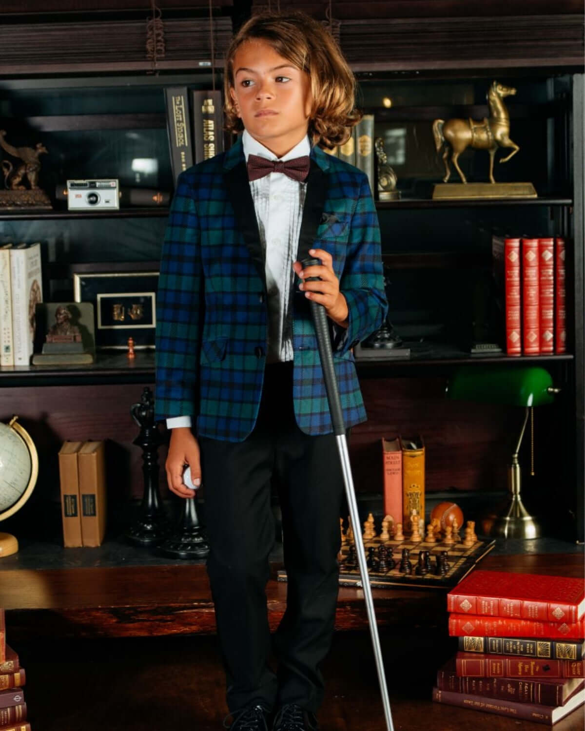 Dapper kid wearing a Blackwatch Velvet Plaid tuxedo jacket, exuding playful sophistication for stylish adventures.