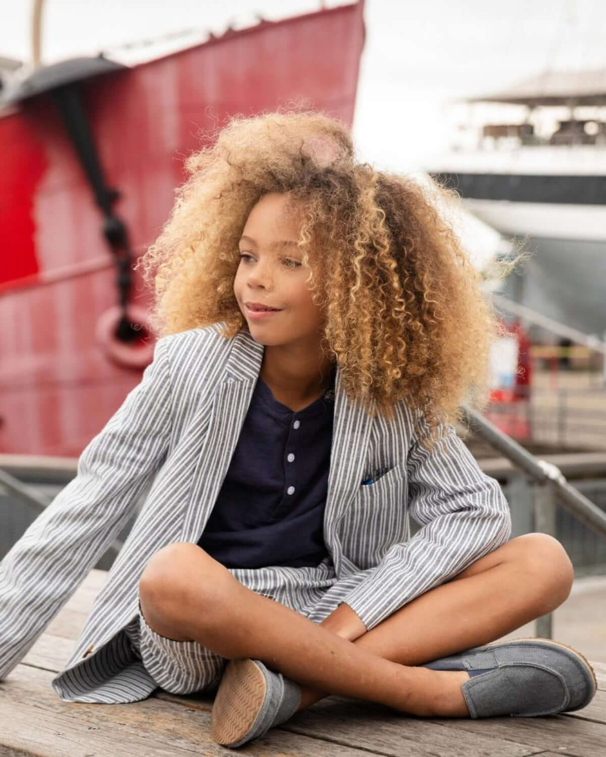 Chic kid in navy stripe linen jacket and shorts, exuding style by the waterfront—perfect for back to school adventures!