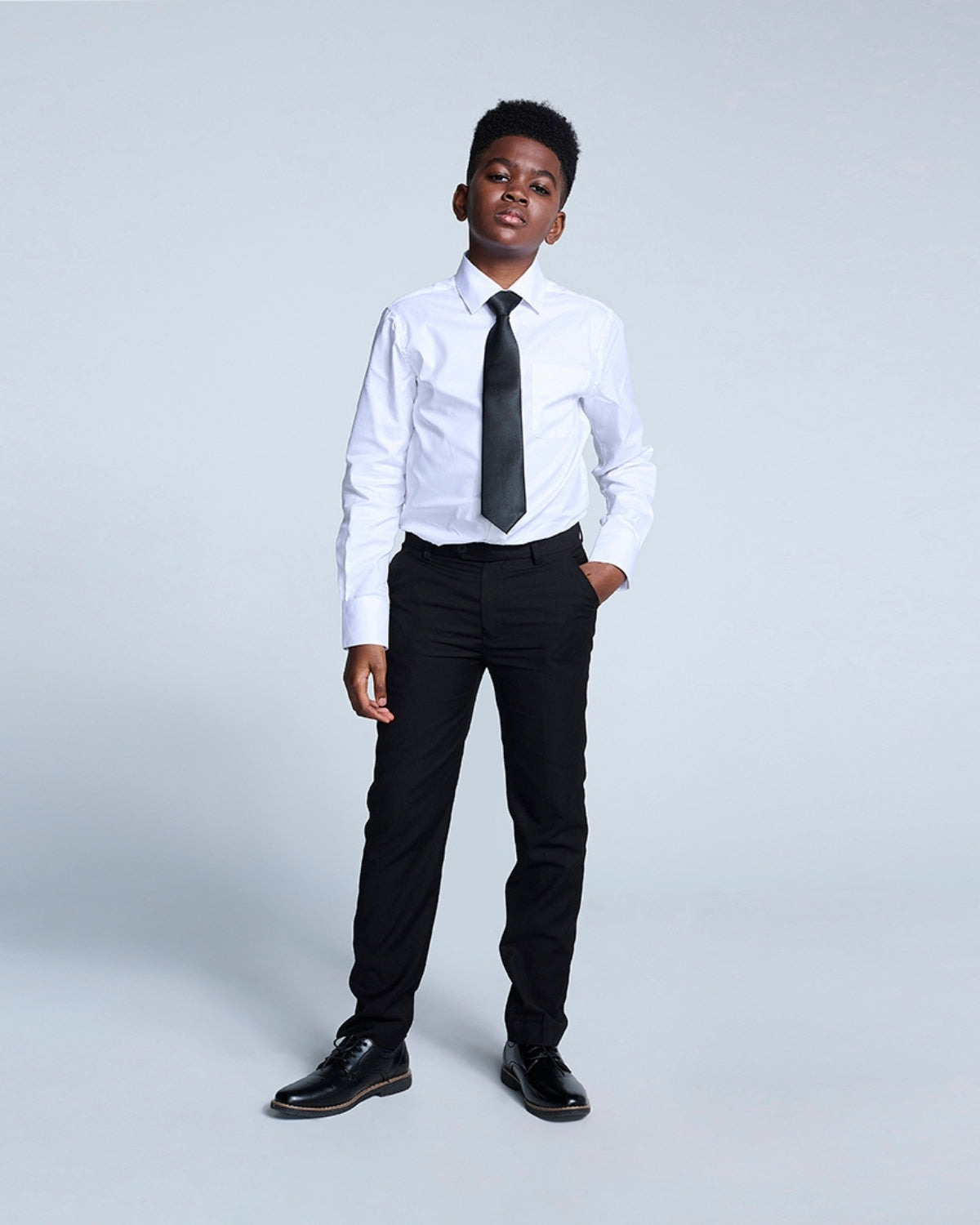 Stylish kid in a white shirt and slick black suit pants, ready for school or a special event in high-quality kids clothes.