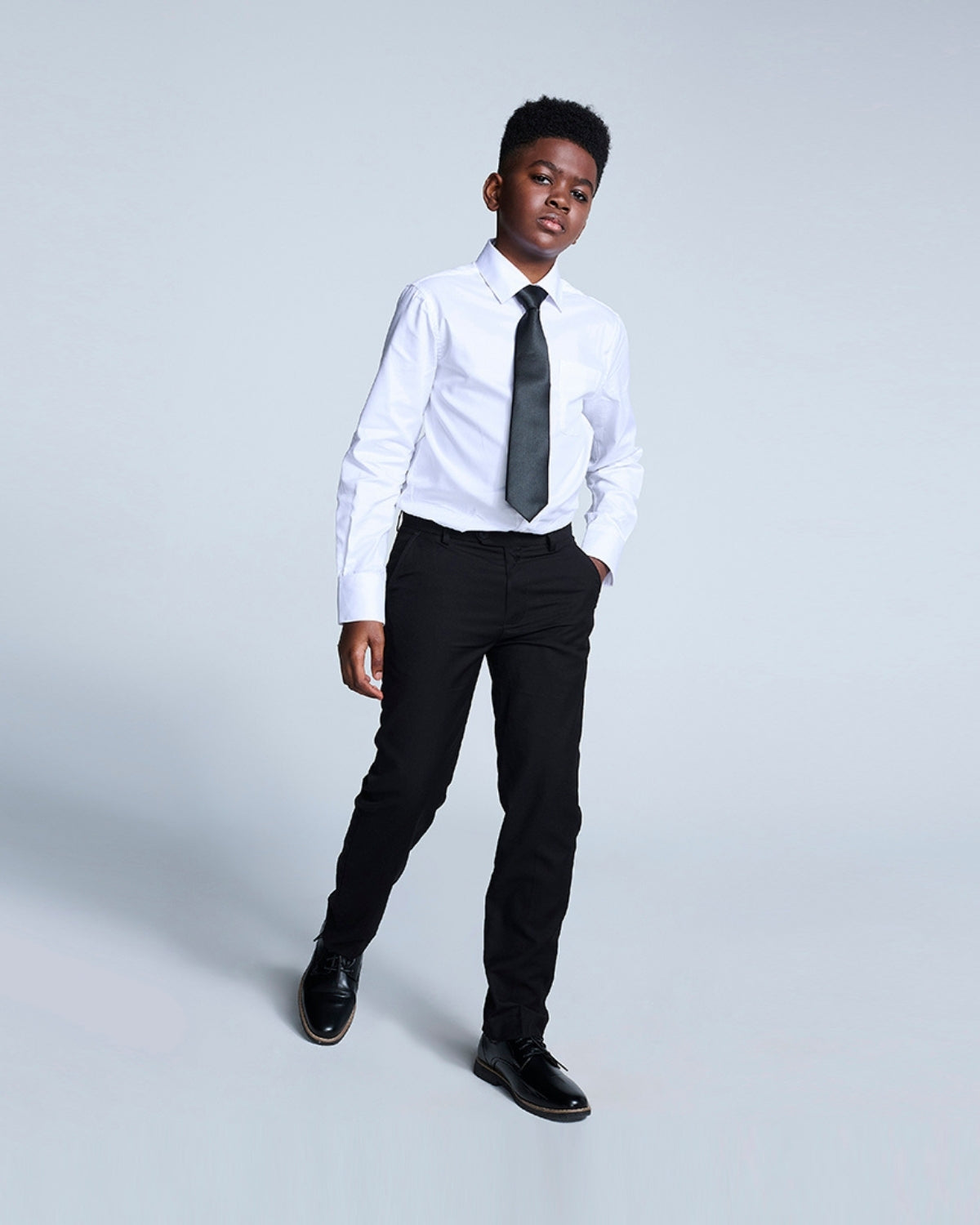 Stylish boy in black suit pants and tie, ready to shine at any formal event—back to school never looked so good!