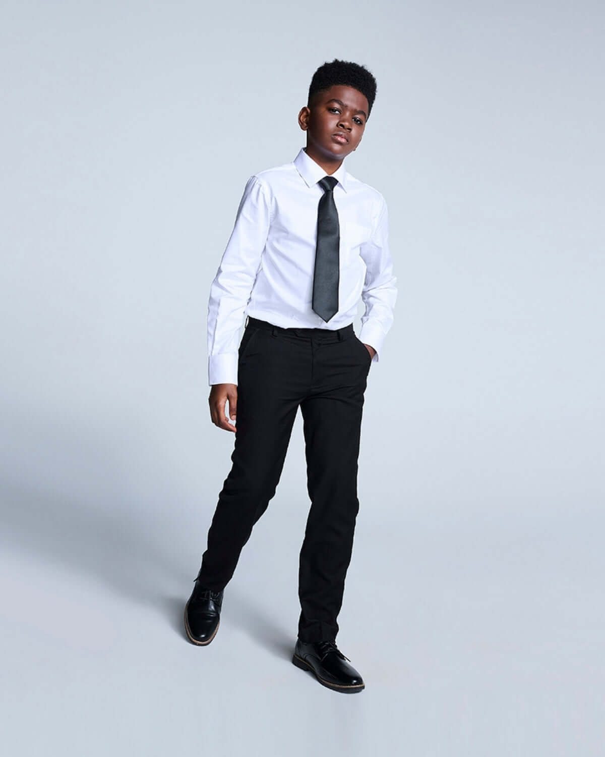 Stylish boy in black suit pants and tie, ready to shine at any formal event—back to school never looked so good!