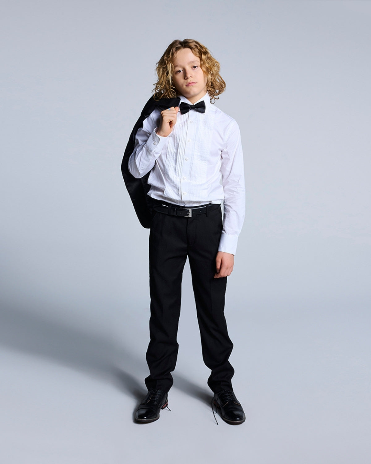 Stylish kid rocking black tuxedo pants and bow tie, ready to shine at any formal event like a mini trendsetter!