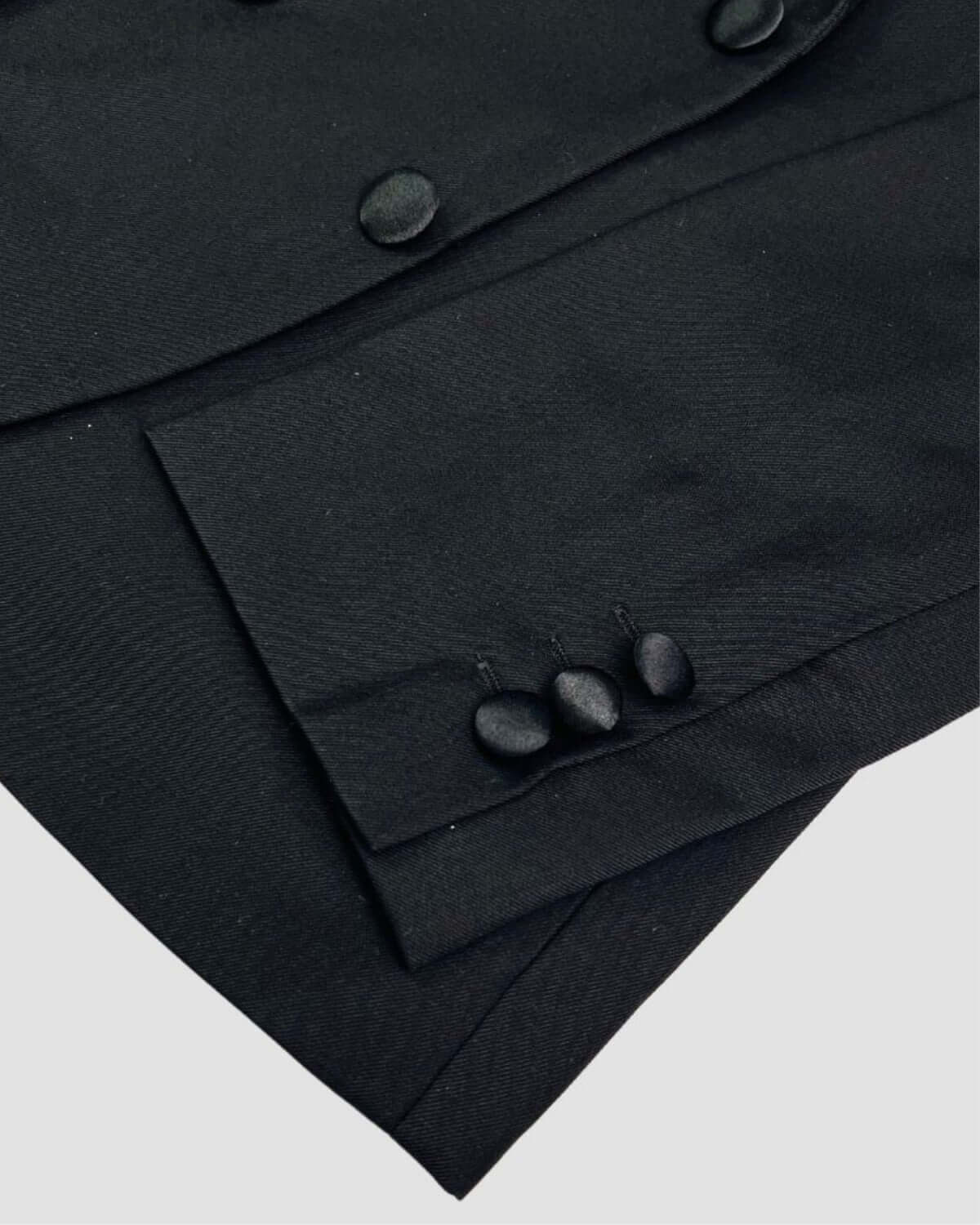 Close-up of a stylish black tuxedo jacket showcasing satin collar and sleek buttons—great kids clothes for formal events.