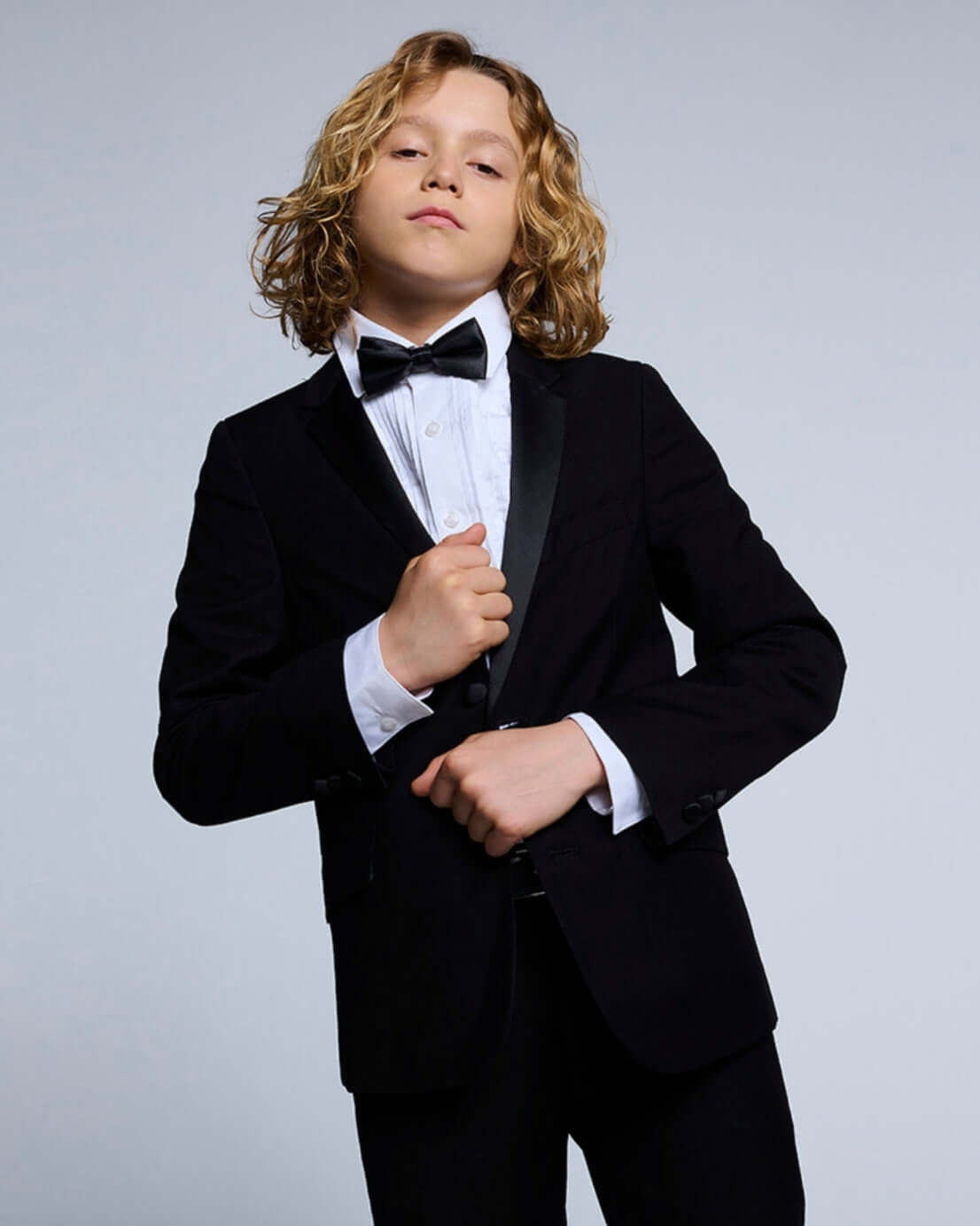 Black Tuxedo Suit Jacket worn by a young boy with a bow tie, perfect for formal events.