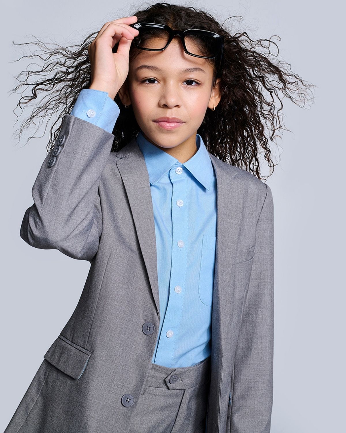 Cool kid rocking a blue standard shirt under a stylish gray suit—ready to shine in high-quality kids clothes!