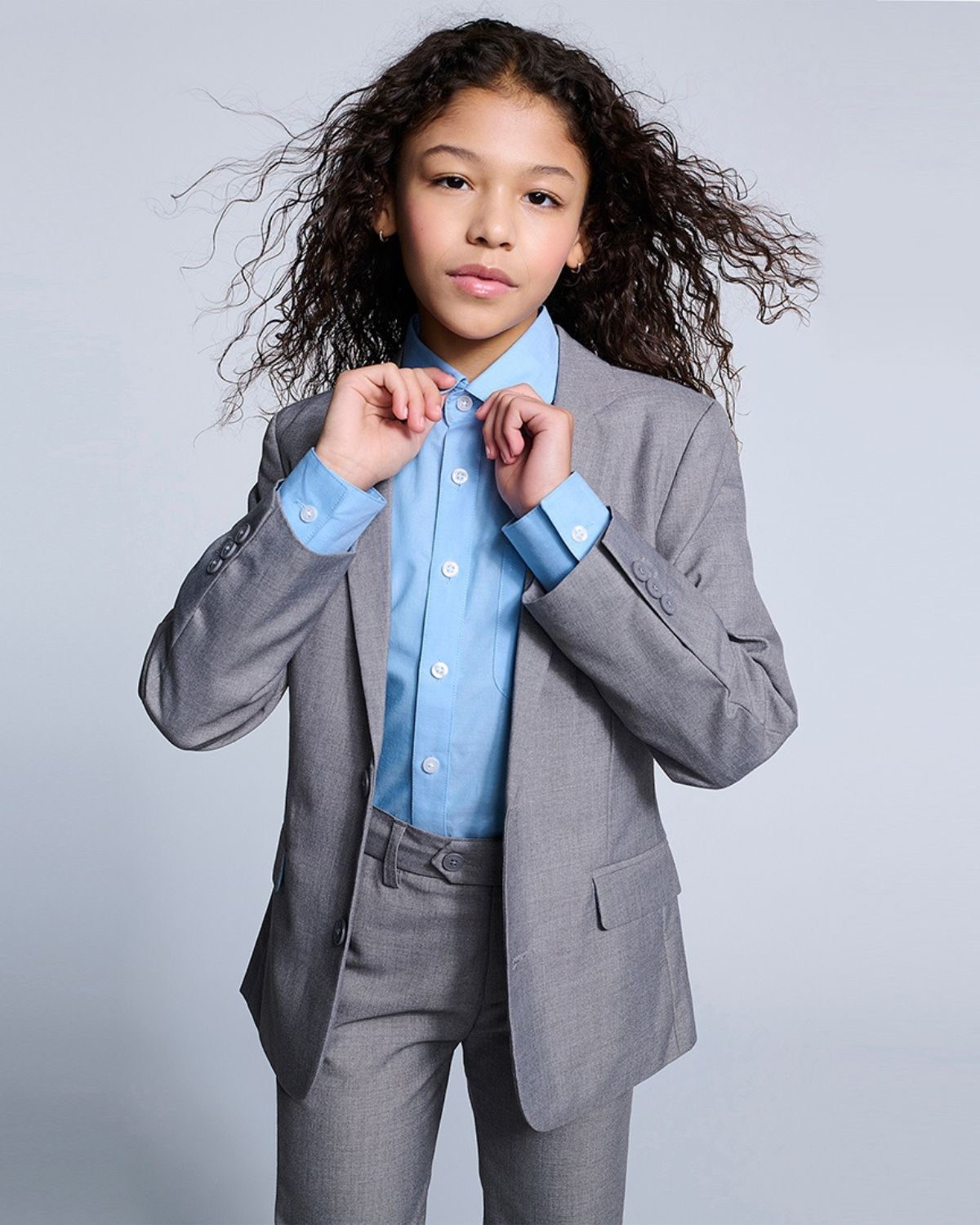 Chic kid in a tailored gray suit and bright blue shirt, ready to make a stylish impression at any event!
