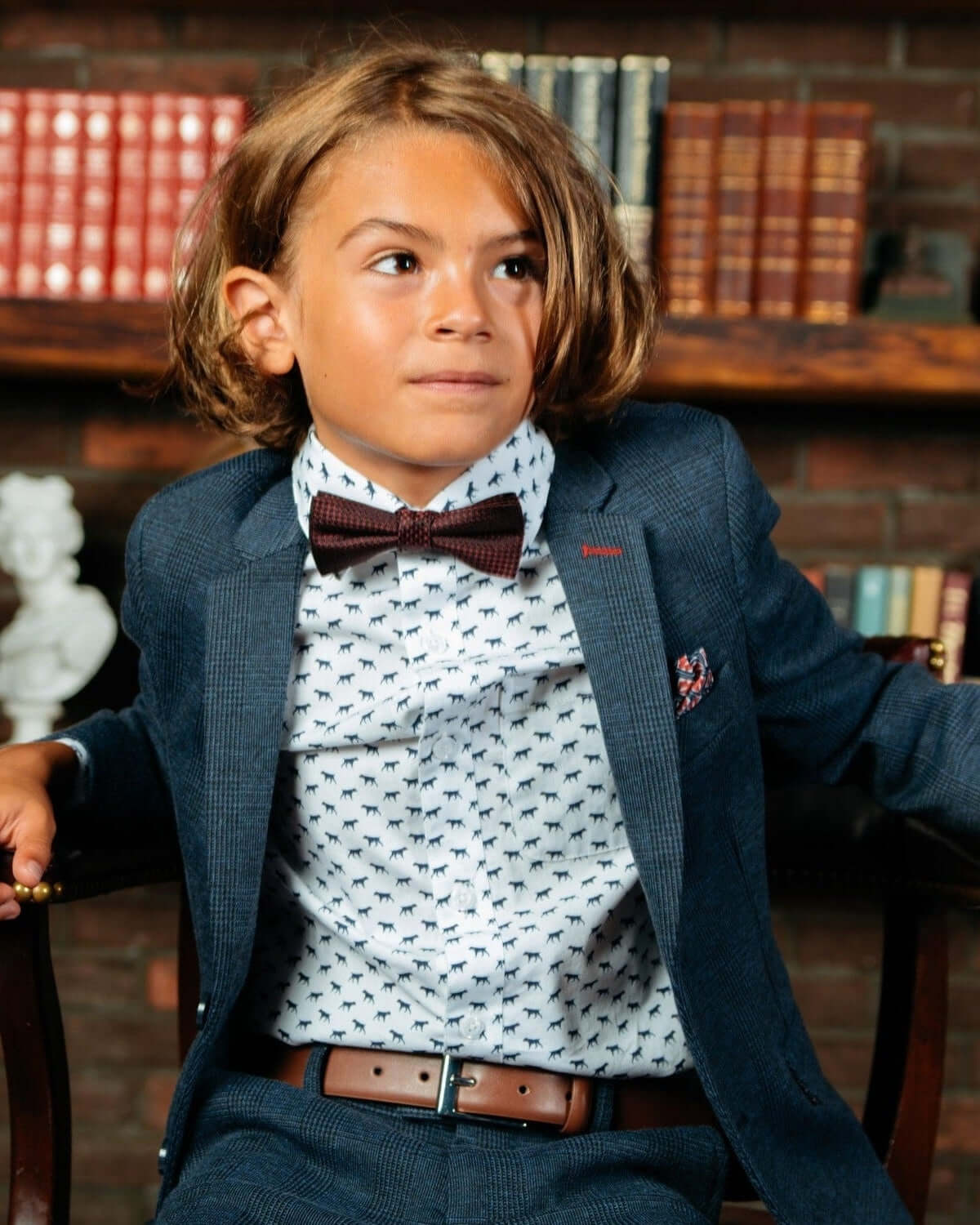 Boy dressed in formal attire with a brown dress belt, showcasing a stylish look with a bow tie.