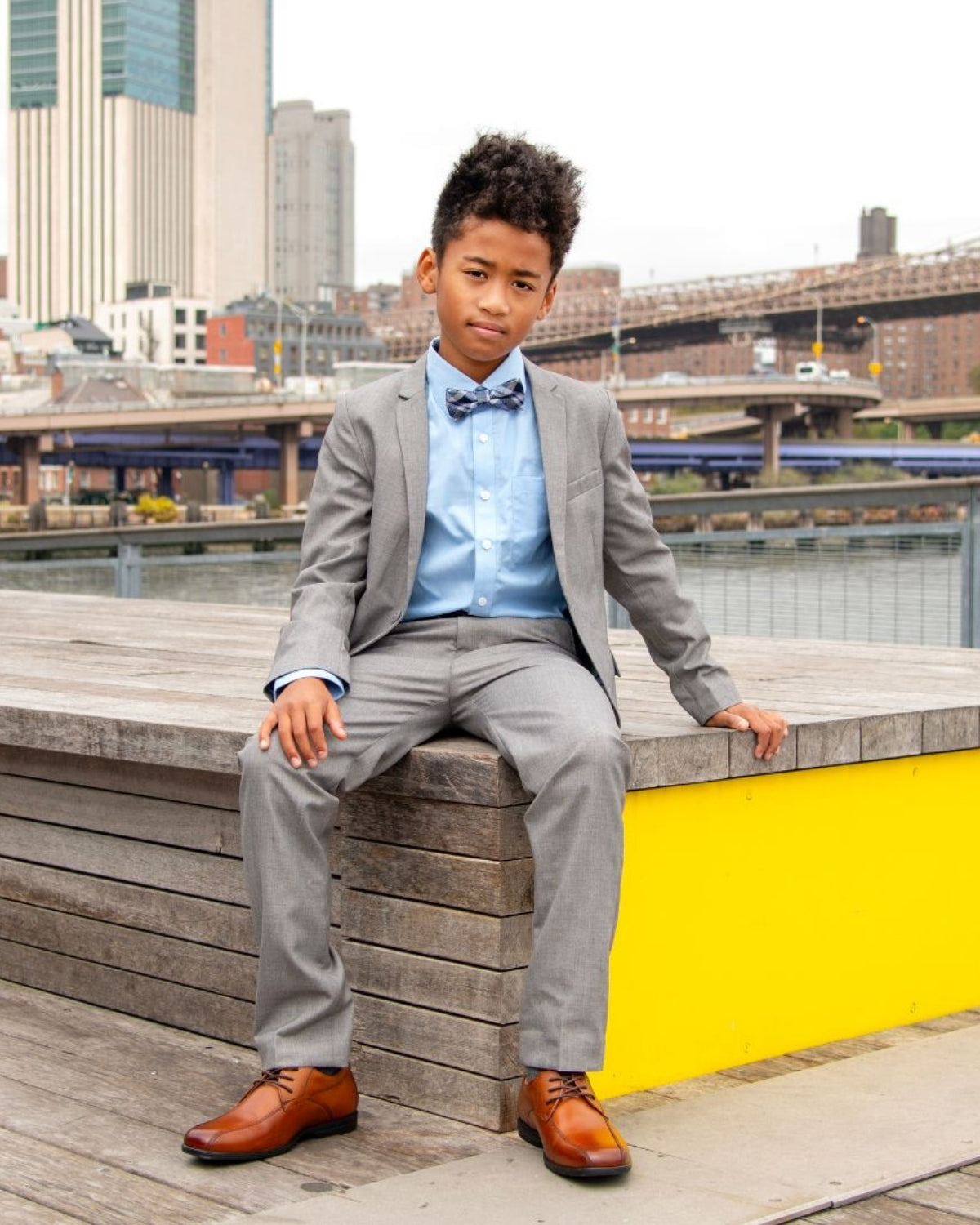 Stylish young boy in gray suit and bow tie, showcasing high-quality kids clothes for back to school events.