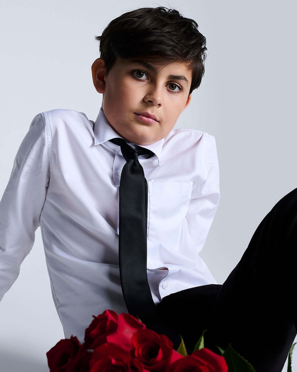 Stylish boy in a premium white dress shirt and tie, exuding confidence with roses—perfect for kids clothes and formal events!
