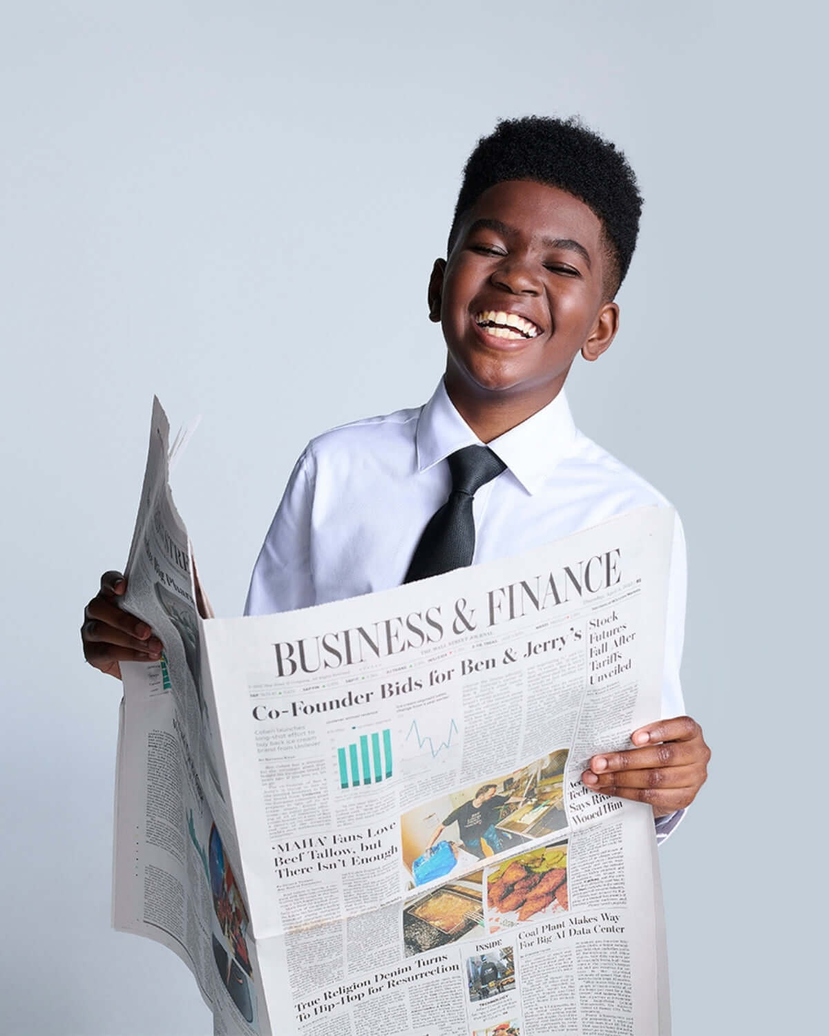Young boy in a stylish white dress shirt and tie, joyfully holding a business newspaper, ready to take on the world.