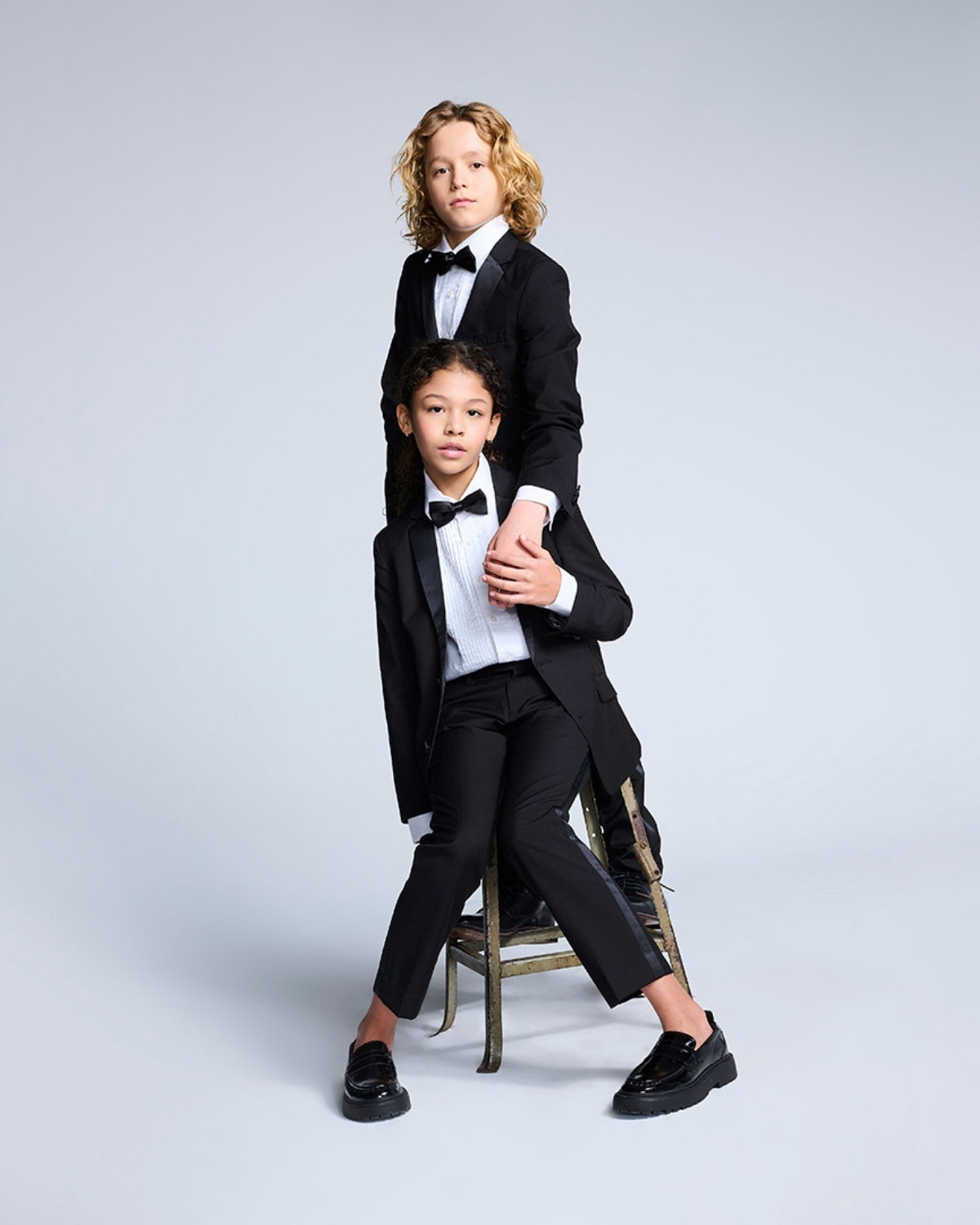 Stylish kids in tuxedos showcasing playful elegance—perfect boys' and girls' clothes for upscale events or back to school!
