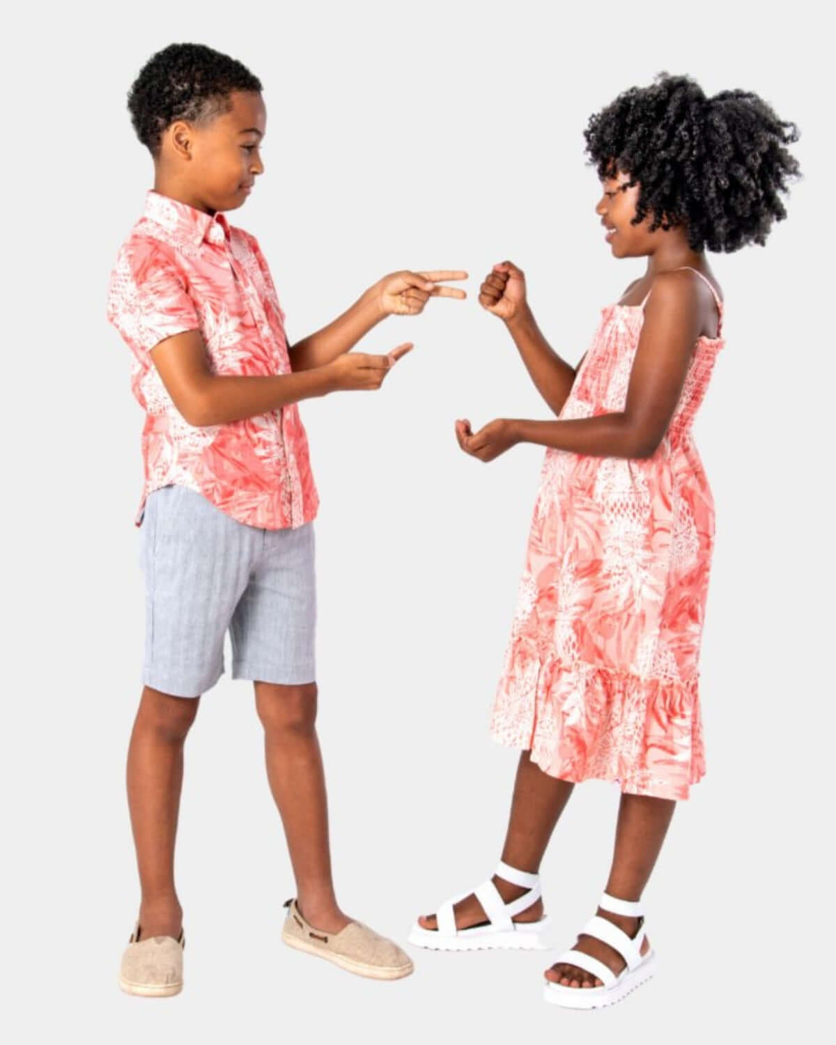 Children wearing Coral Pineapples Day Party Shirt and dress, playing rock-paper-scissors in a fun party setting.