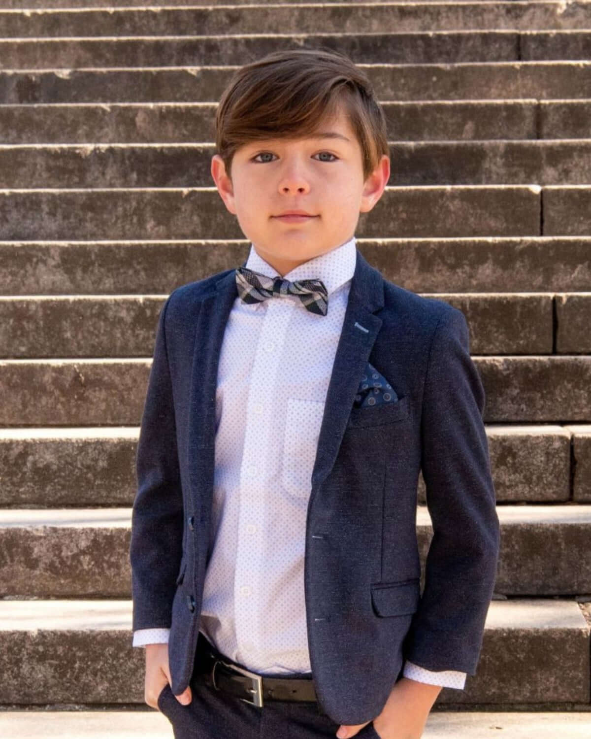 Stylish boy in a tailored suit with a bow tie, ready to shine in high-quality kids clothes for back to school.