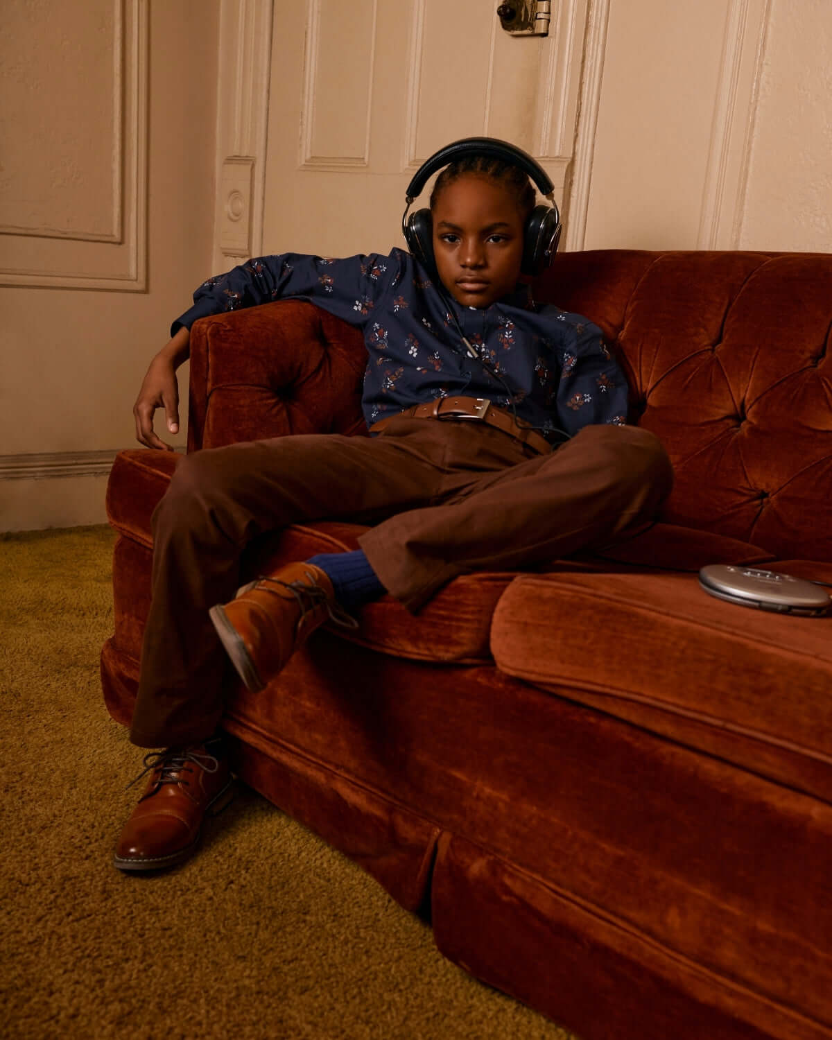 Stylish kid lounging on a vintage couch in a midnight floral button-down, ready for play or relaxation in high-quality kids clothes.