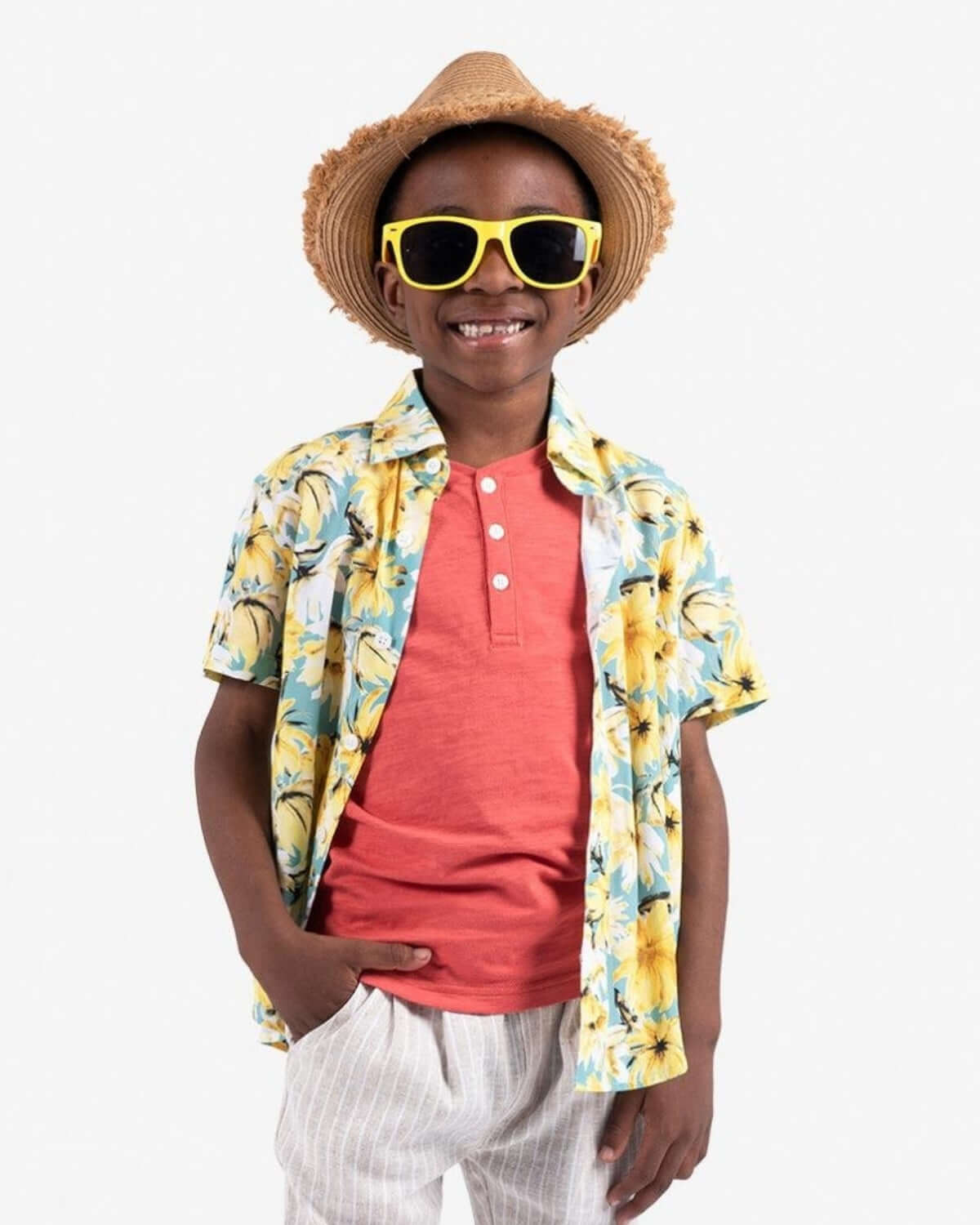 Stylish kid rocking a fun floral party shirt, bright shades, and a straw hat—ready for sunny adventures! Perfect boys' clothes.