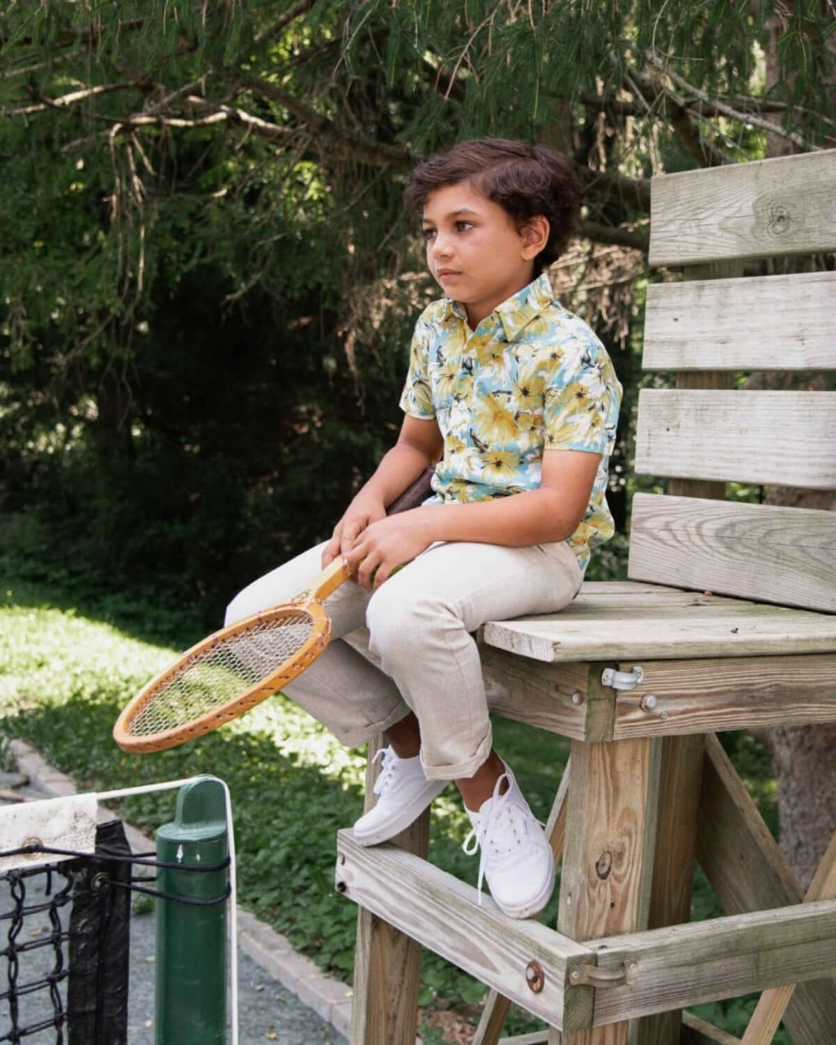 Stylish boy in a bright Spring Bloom Day Party shirt, relaxing on a lifeguard chair, ready for fun outdoor adventures.