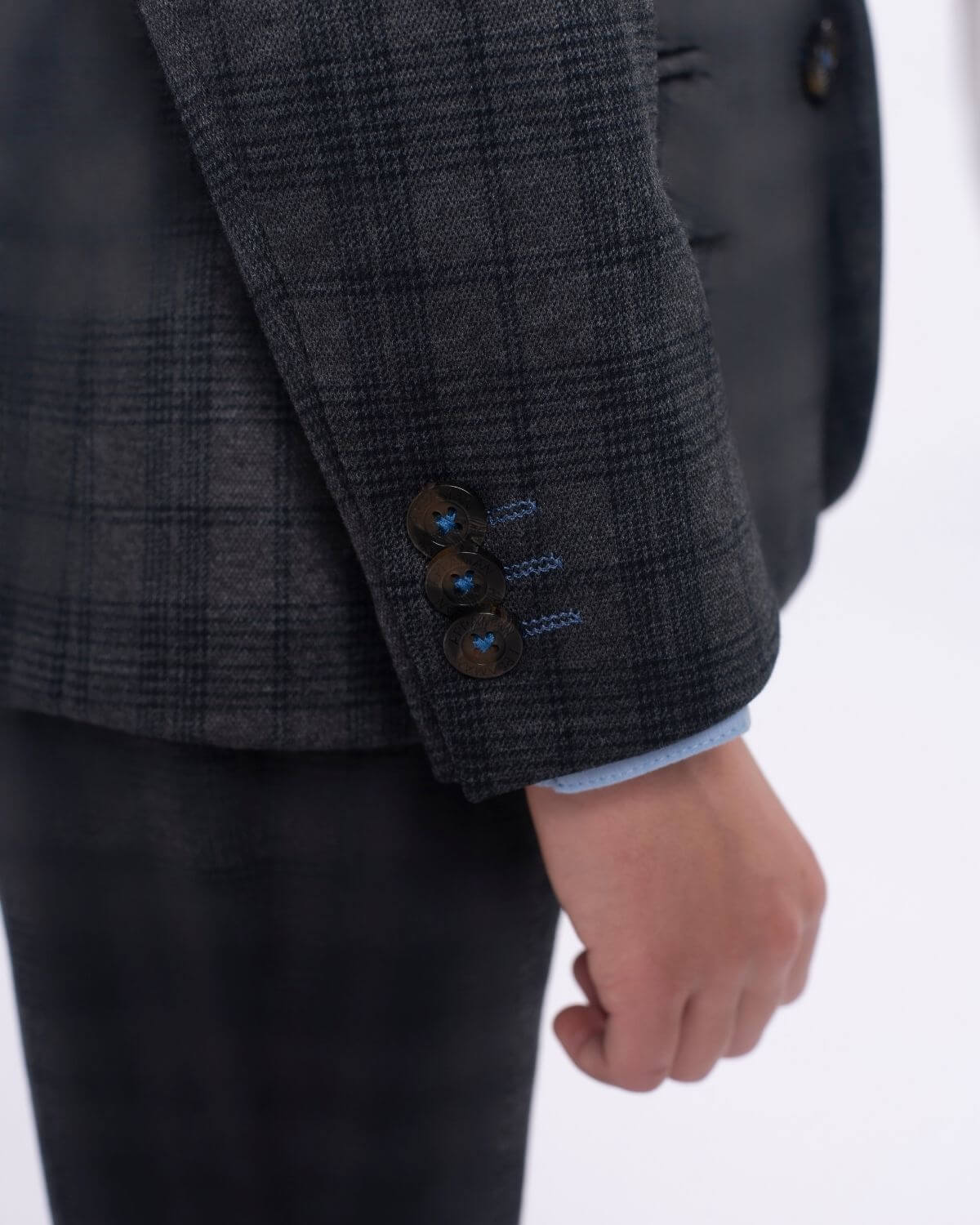 Stylish close-up of a boy's plaid suit jacket showcasing sleek buttons and sophisticated tailoring for trendy kids.