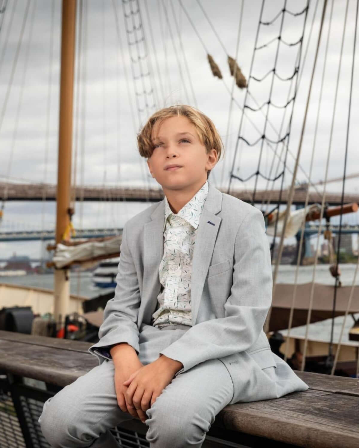 Boy wearing High Rise Grey Stretchy Mod Suit, posing confidently on a ship deck with a scenic background.