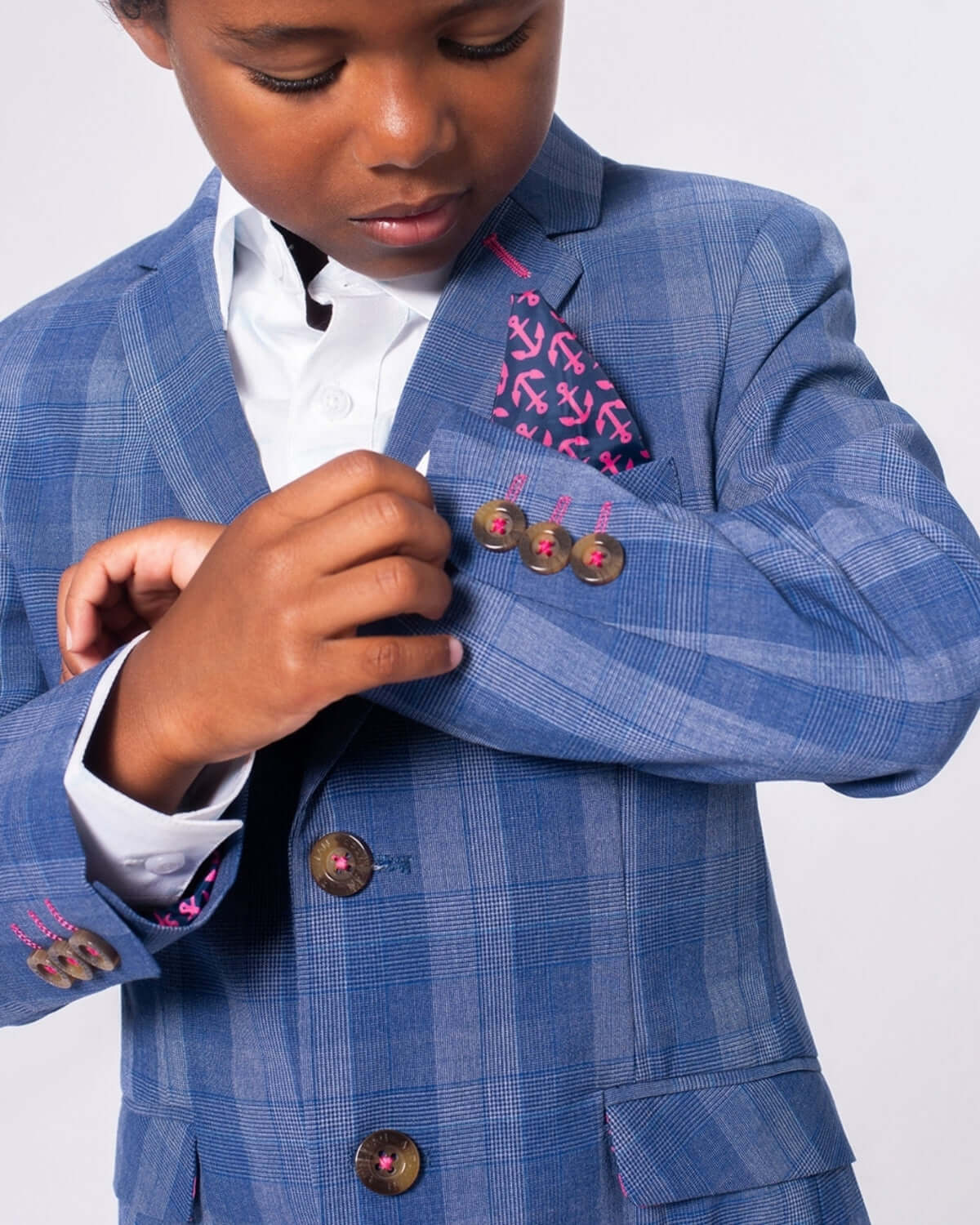 Stylish kid adjusting his Indigo Glen Plaid suit, showcasing playful details and comfort—perfect for weddings or family photos.