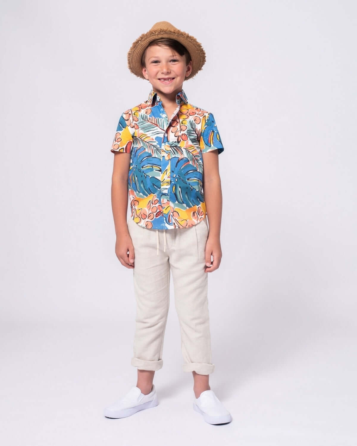 A stylish boy in a colorful floral shirt and hat, ready for summer fun in vibrant kids clothes by Appaman.