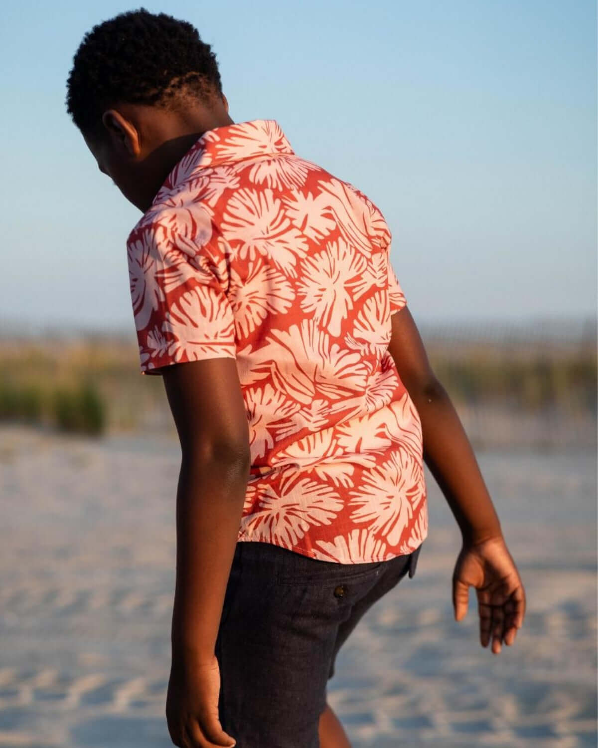 Stylish boy wearing a clay garden party shirt, enjoying a sunny beach day—perfect for back to school fun!