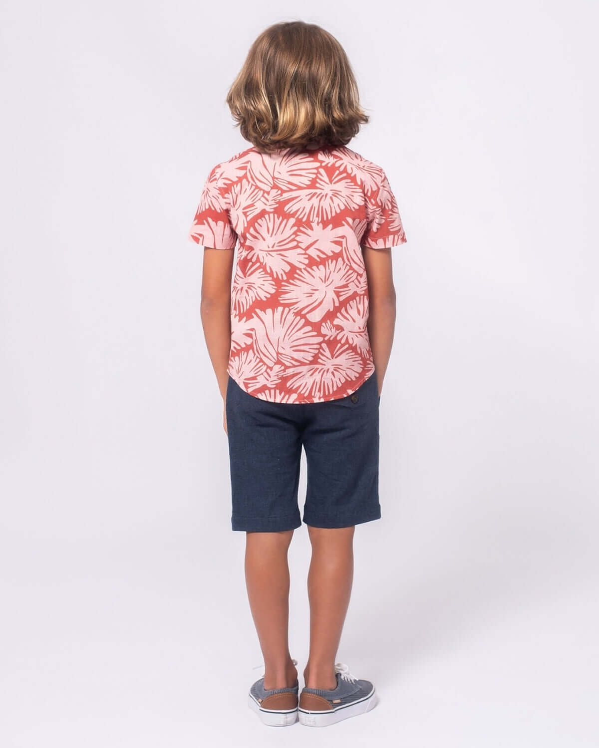 Boy wearing a Clay Garden Day Party Shirt with a playful print, paired with navy shorts and sandals.
