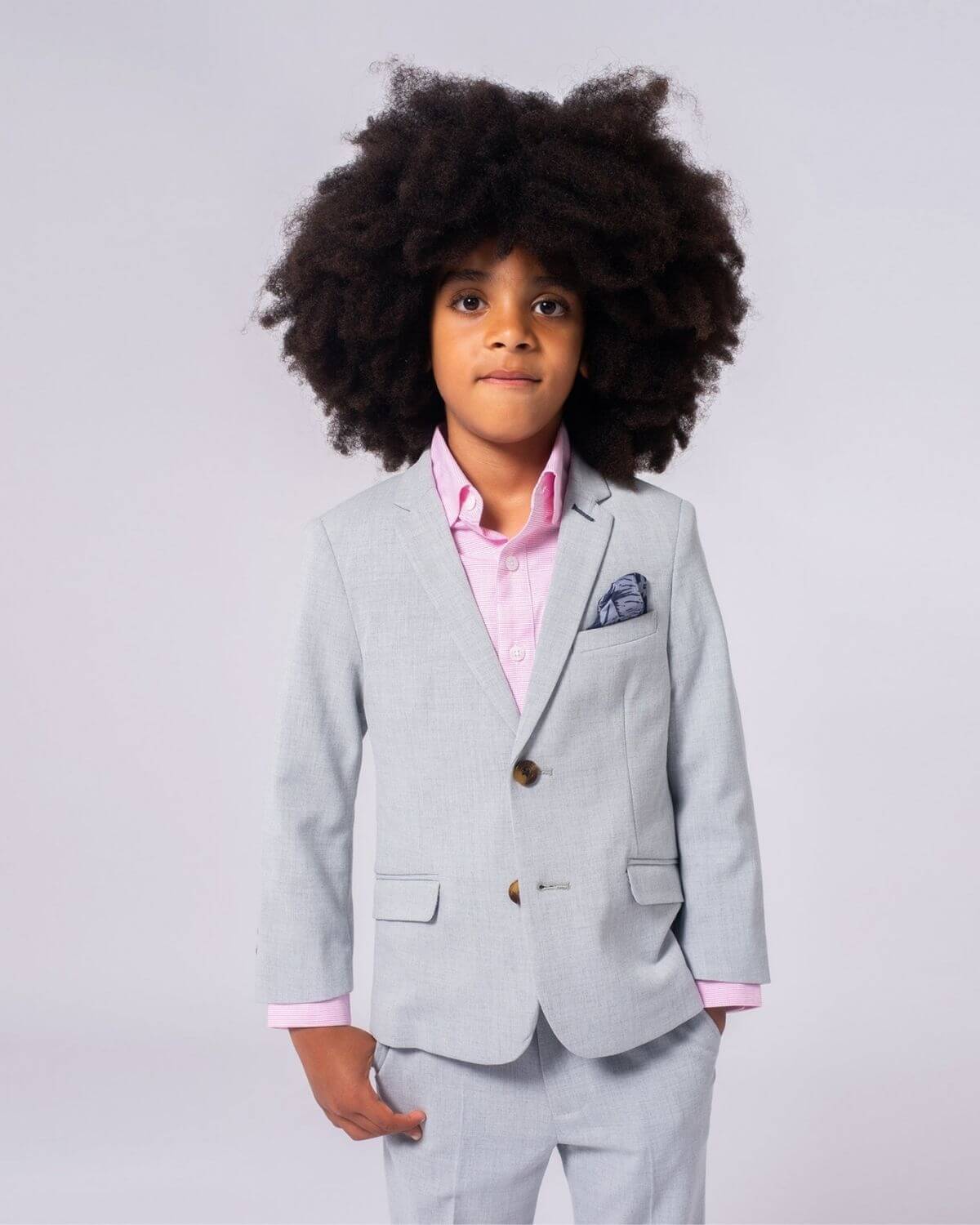 Stylish kid in a light grey suit with a pink shirt, showcasing high-quality boys' clothes for dressy occasions.