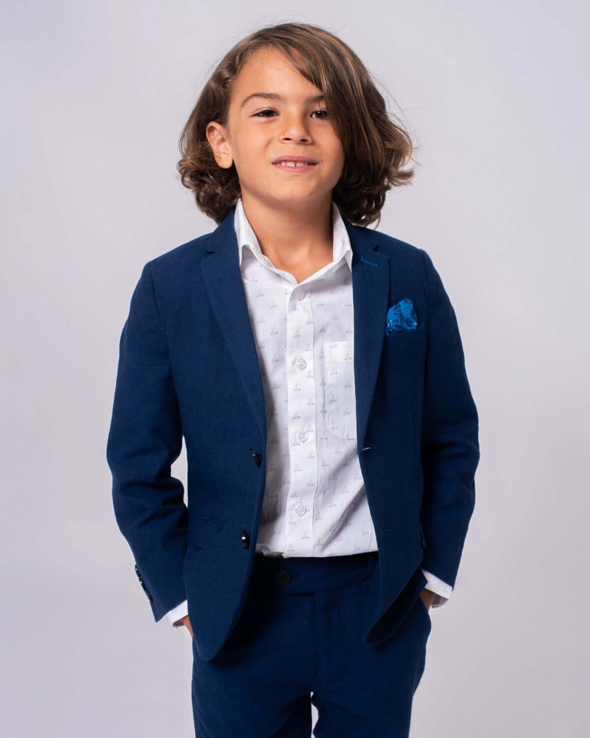 A boy wearing a navy blue suit with a white shirt, featuring the Morning Sail Standard Button Down for a stylish look.