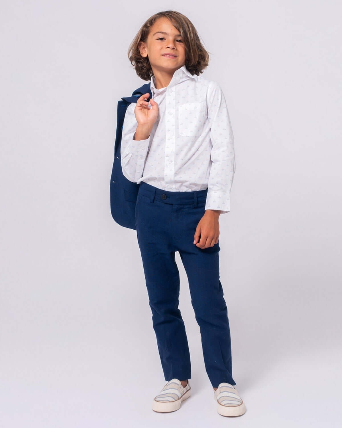 Stylish boy in a fun button-down shirt and navy pants, ready for back to school adventures with a cool backpack in tow!