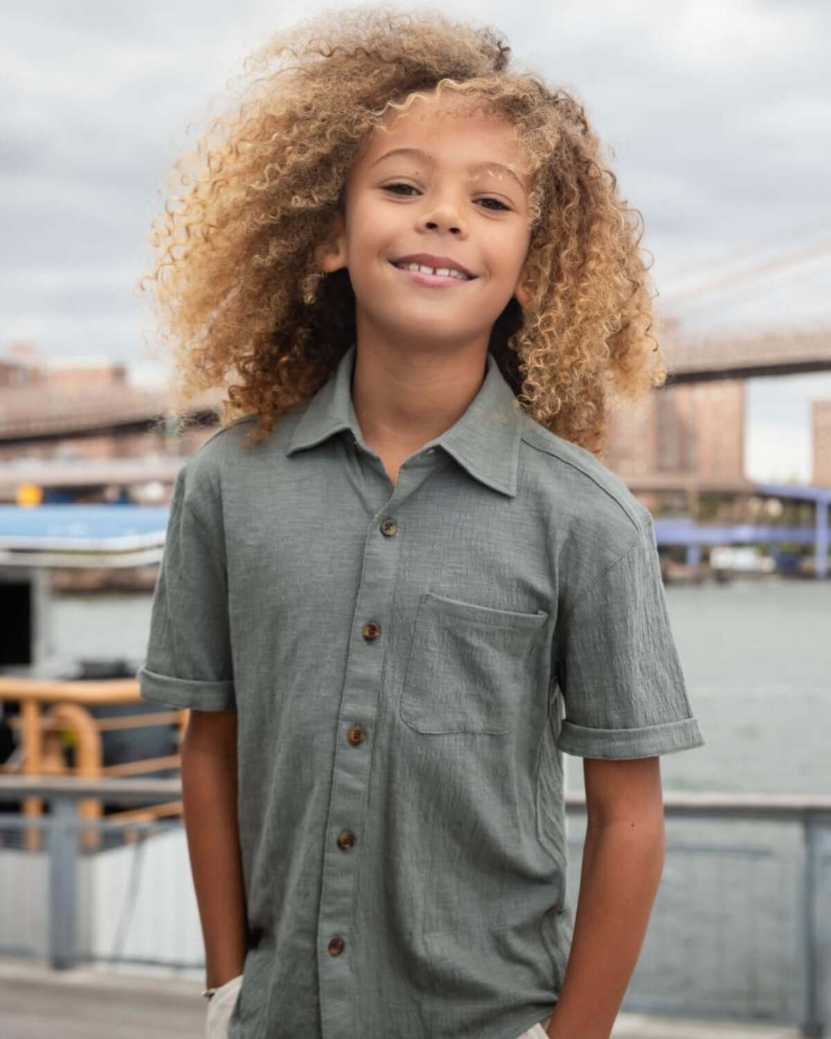 Sage Beach Shirt model smiling by the water, showcasing its lightweight and stylish design for summer adventures.