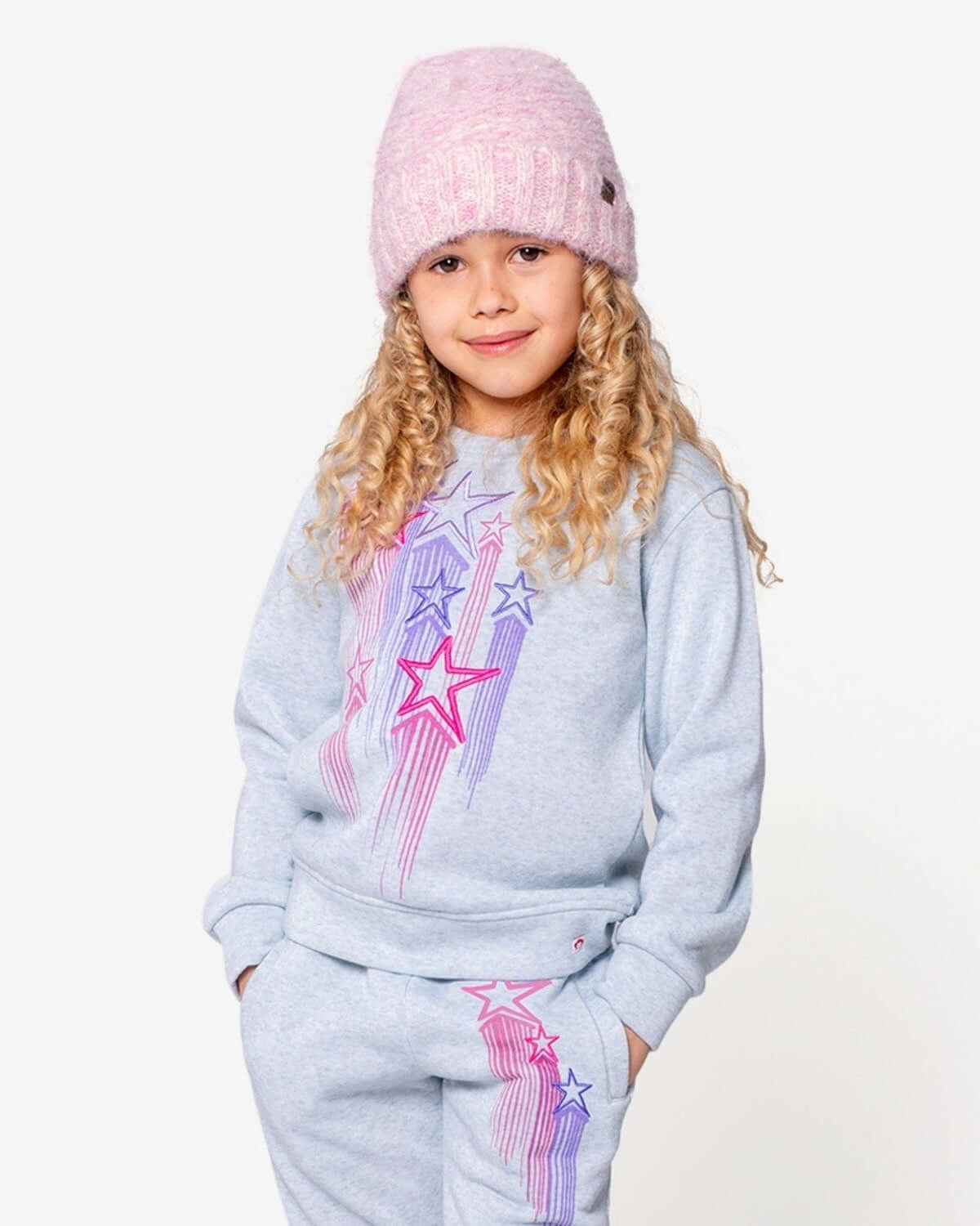 Trendy little girl in a soft pink beanie and stylish star-print sweatshirt—perfect for back to school adventures!