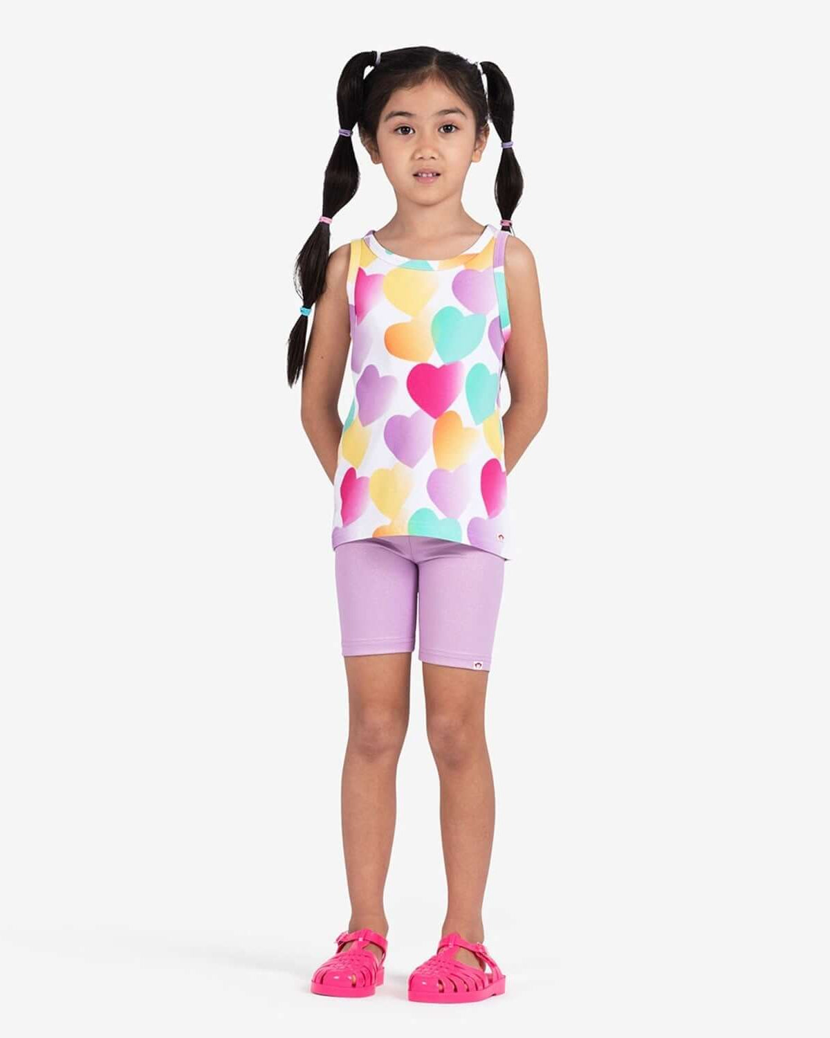 Little girl wearing Sparkle Lavender Bike Shorts with a colorful heart-patterned tank top.