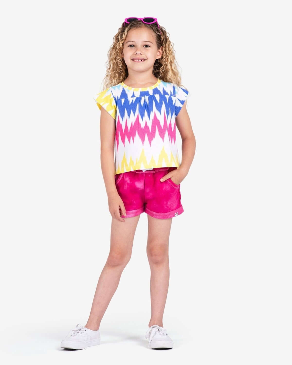 Bold, playful girl in tie-dye top and fuchsia marble shorts—ready for fun adventures in stylish kids clothes!