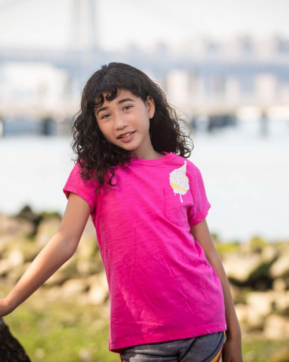 Stylish girl in a bright pink tee with cute ice cream detail, ready for summer fun in high-quality kids clothes.