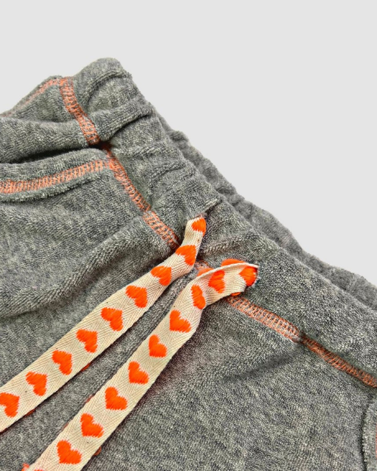 Close-up of stylish Grey Majorca Shorts featuring playful orange heart straps, perfect for kids' summer adventures.