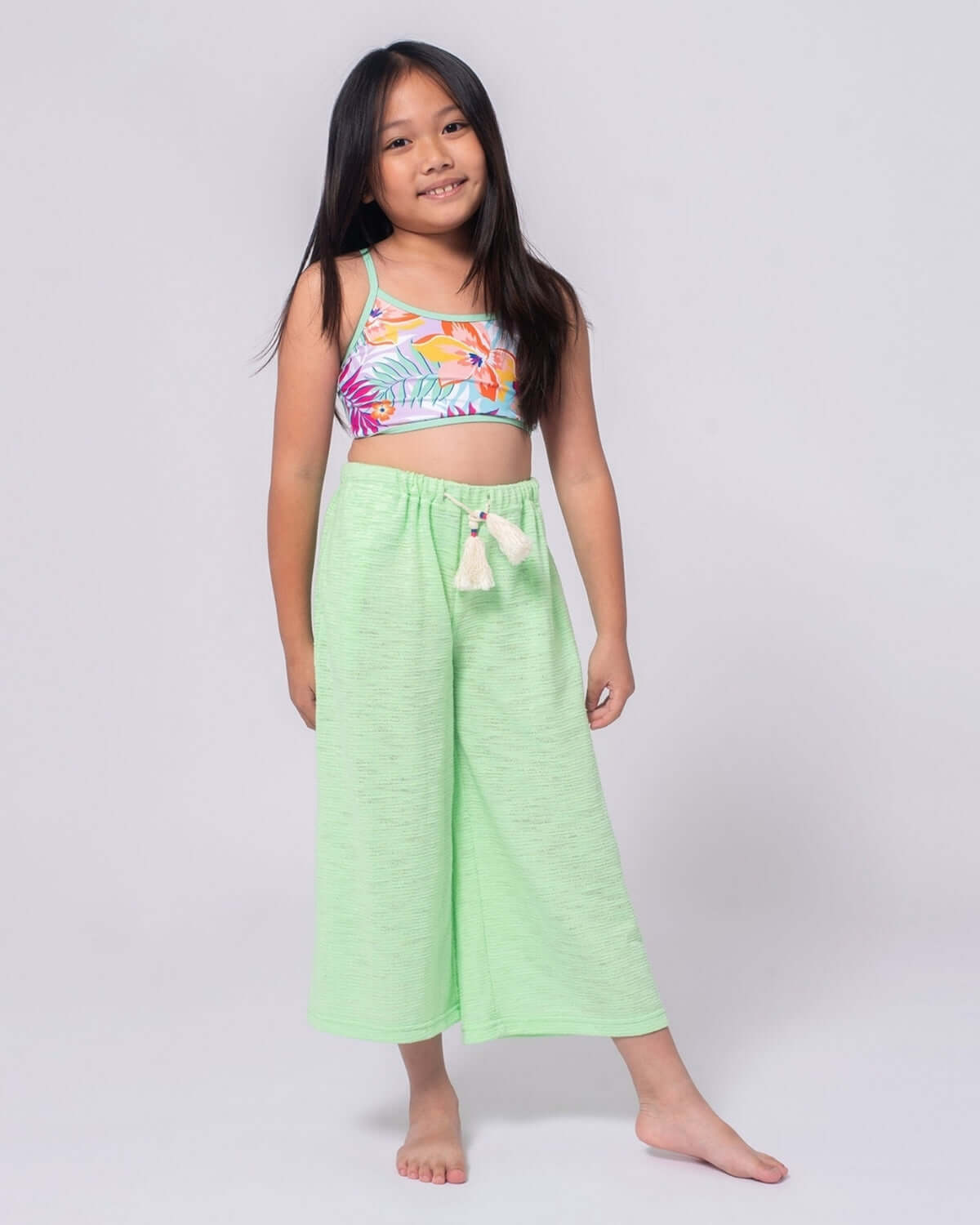 A girl wearing a colorful top and Mint Beach Pant, showcasing a playful summer style for outdoor adventures.
