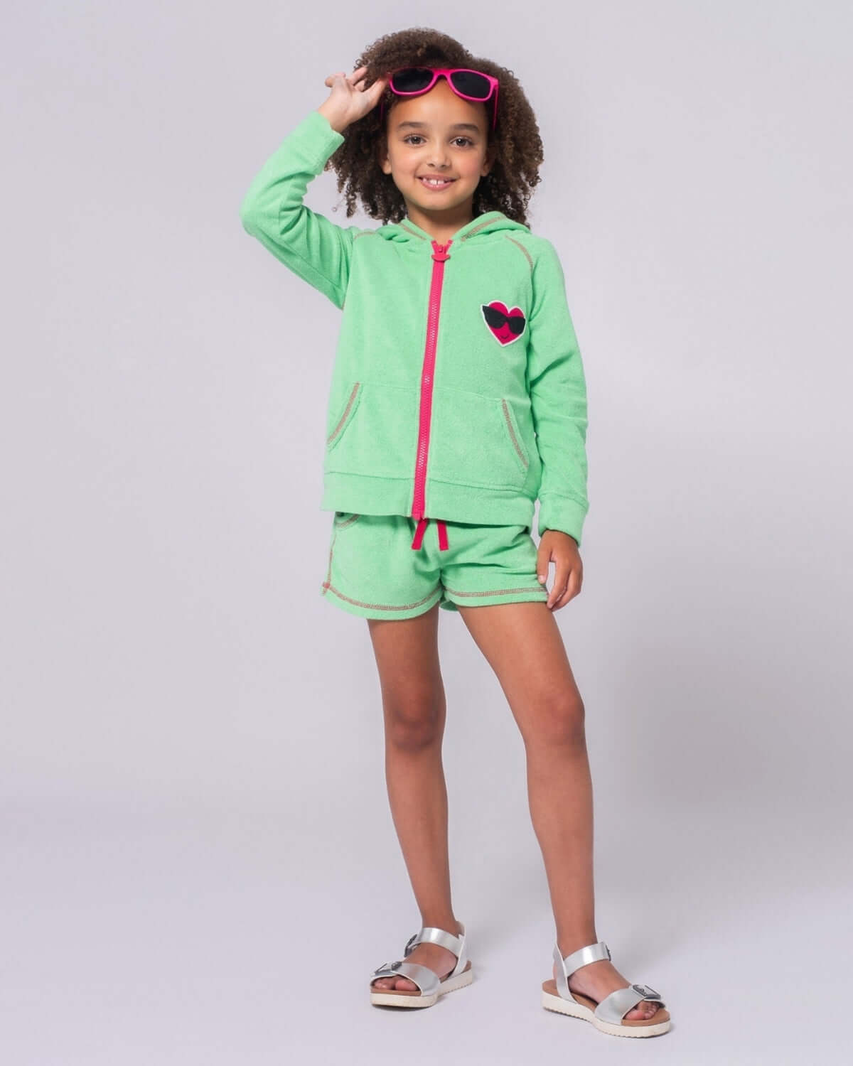 Girl wearing Mint Majorca Shorts and a matching green hoodie with heart, styled for summer fun.