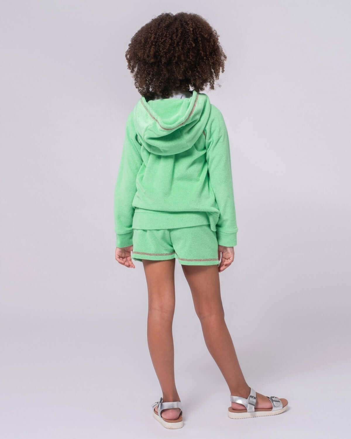 A girl wearing Mint Majorca Shorts and a matching hoodie, showcasing the playful mint hue and comfortable design.
