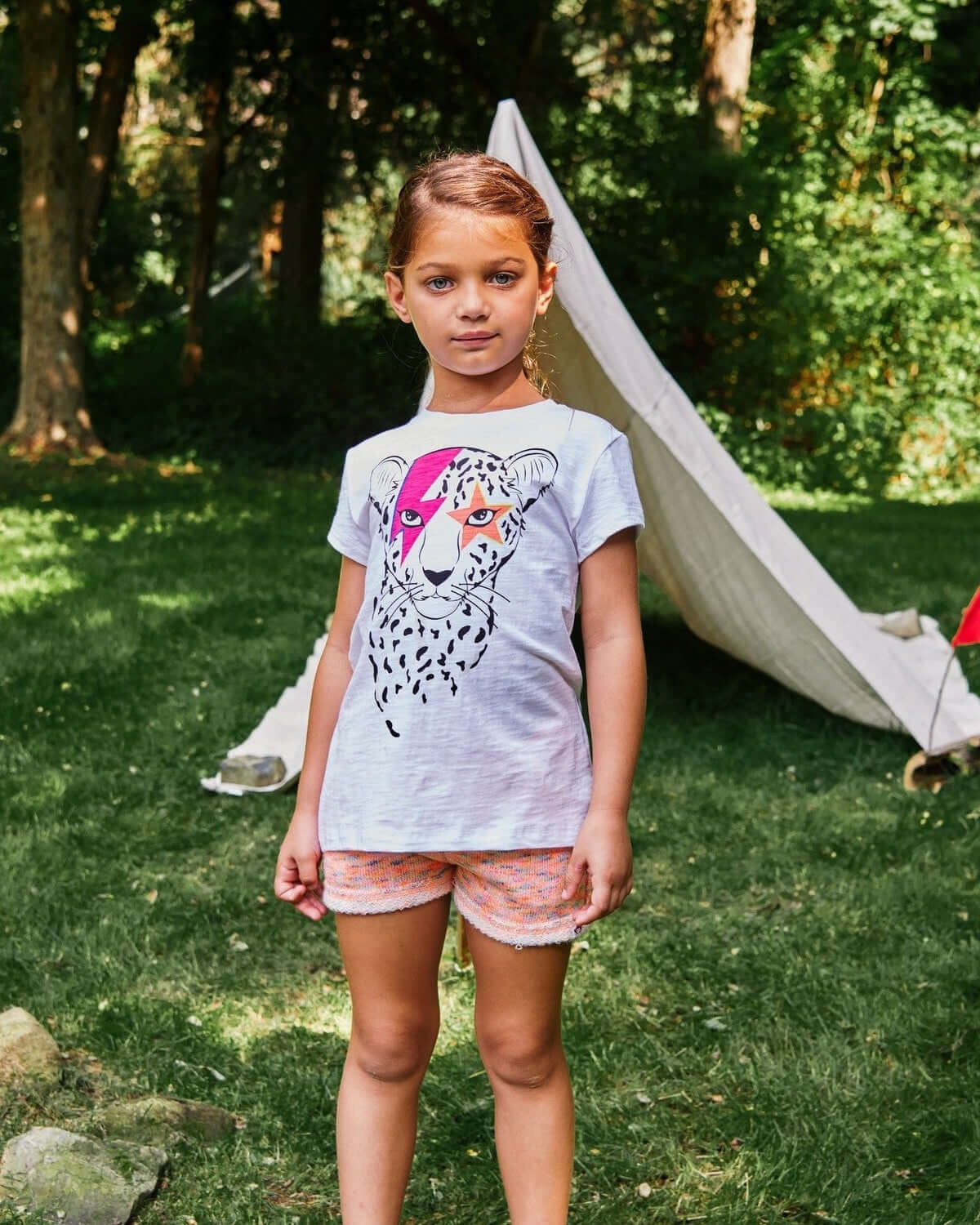 A cool kid rocking Appaman's fun cheetah tee and playful multicolor shorts, perfect for outdoor adventures!